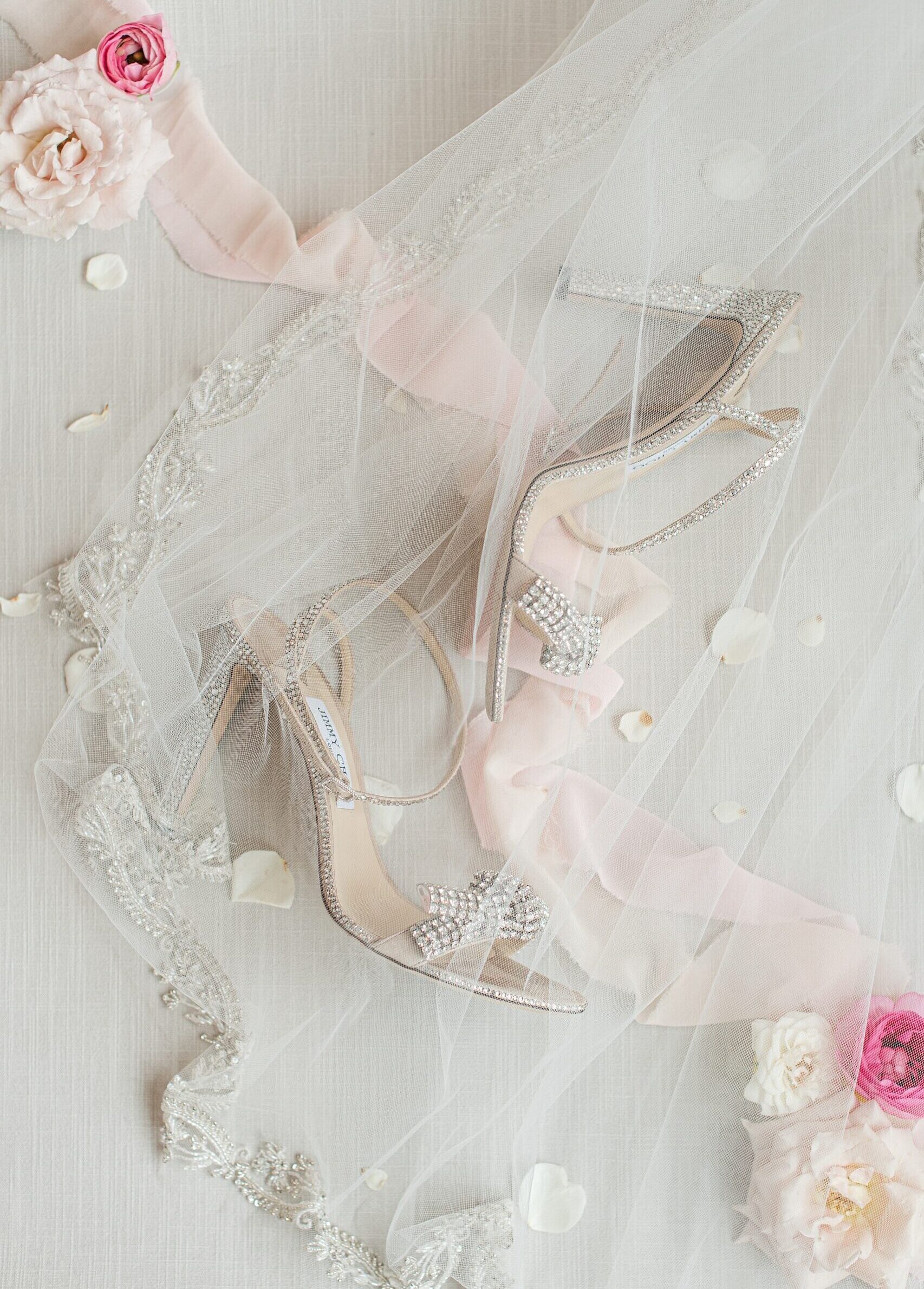 Details of a bride's shoes under a veil with flowers on a table