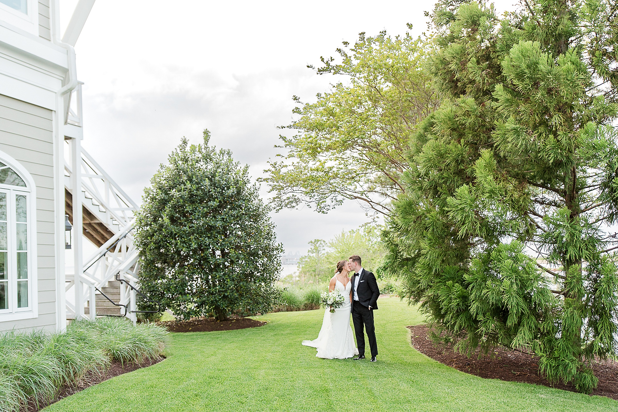 Newlyweds kiss while walking through the side lawn at one of the Baltimore Country Club Weddings