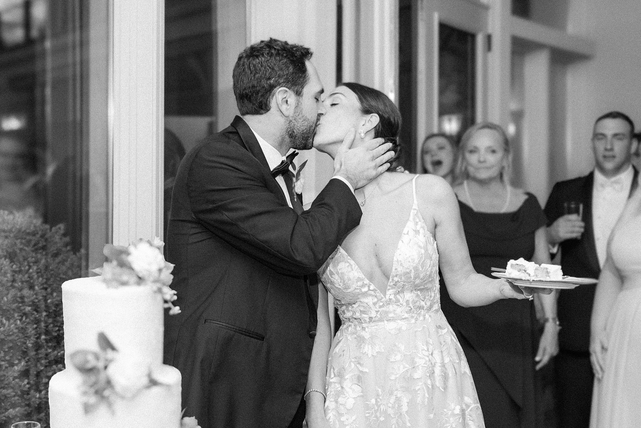 Newlyweds kiss while cutting the cake at their reception in one of the Baltimore Hotel Wedding Venues