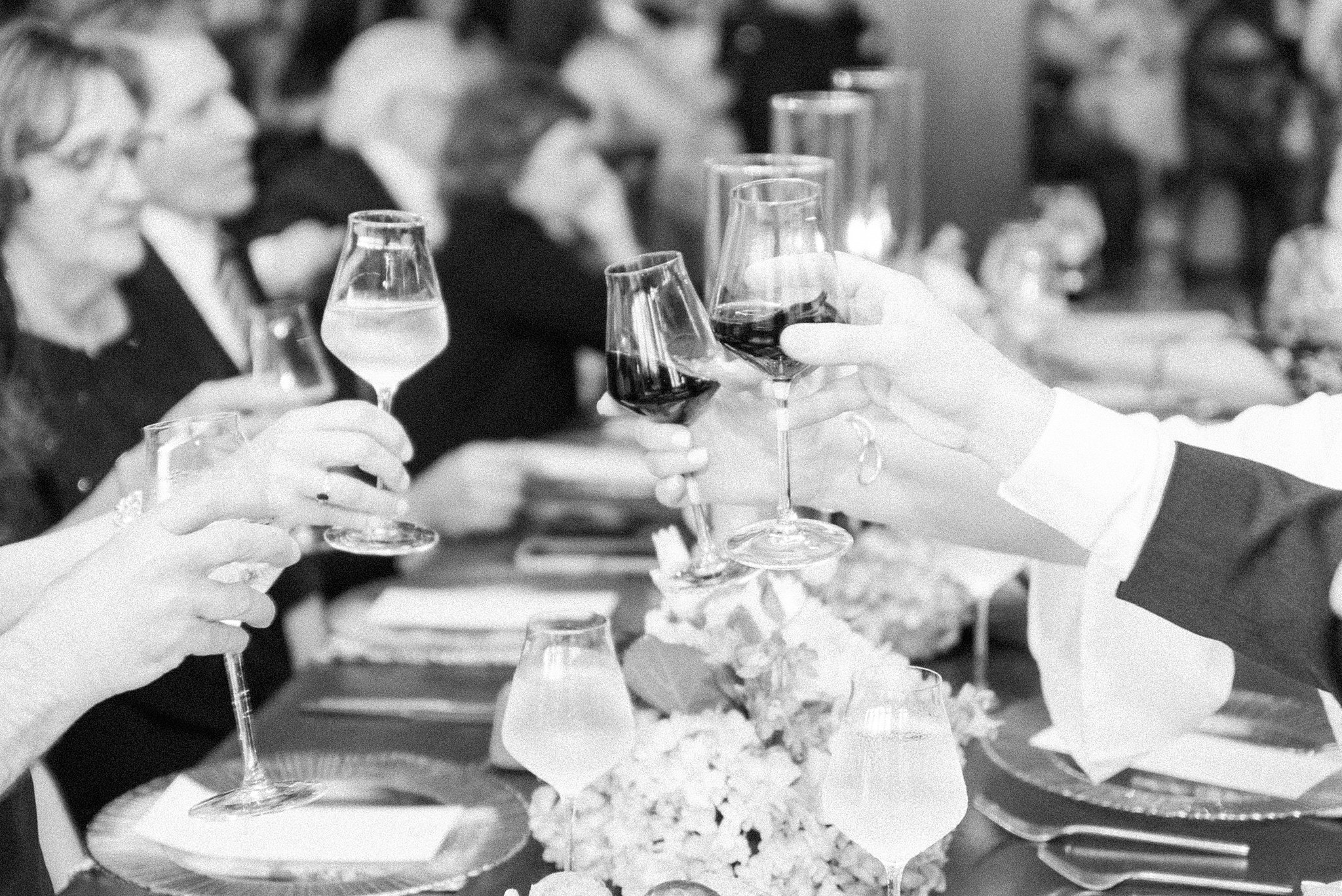 Details of wedding reception guests toasting their wine