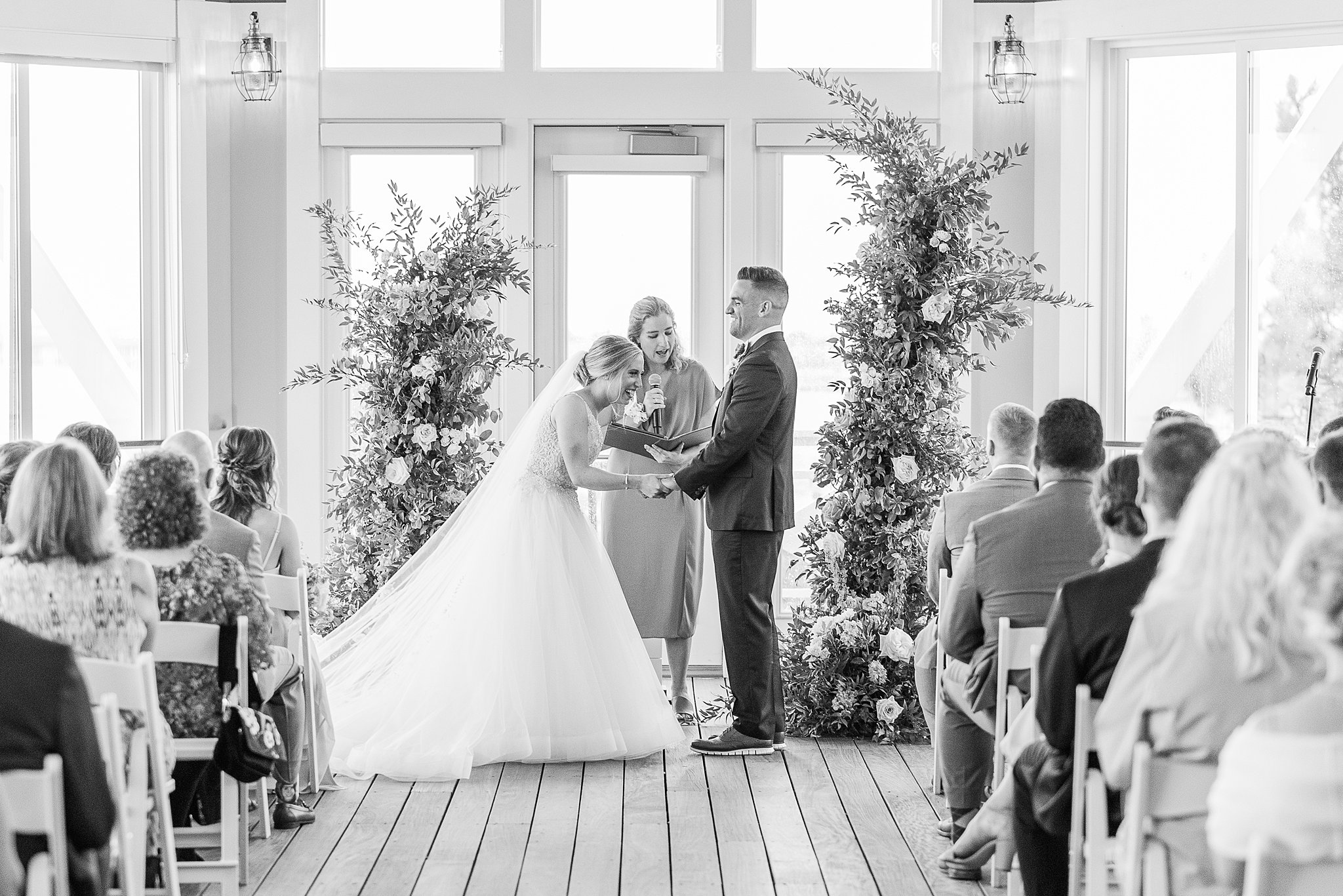 A bride and groom laugh while standing at the altar during their wedding ceremony at one of the Baltimore Hotel Wedding Venues
