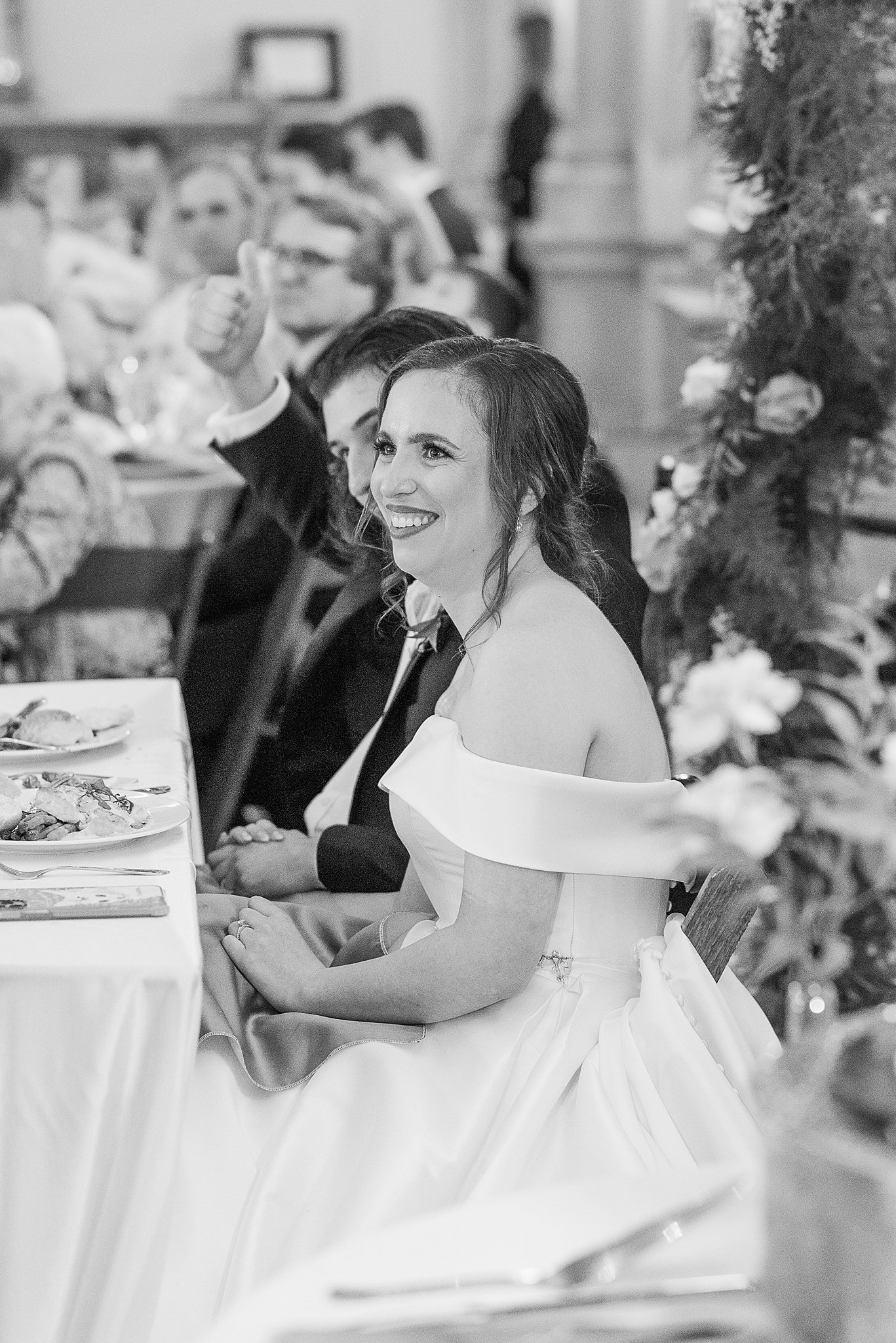 A bride sits and laughs at her head table during toasts at one of the Baltimore Hotel Wedding Venues