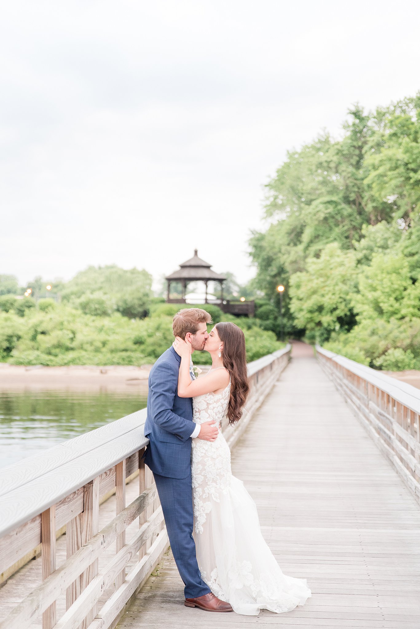 Newlyweds kiss on a long wooden dock at one of the Baltimore Waterfront Wedding Venues