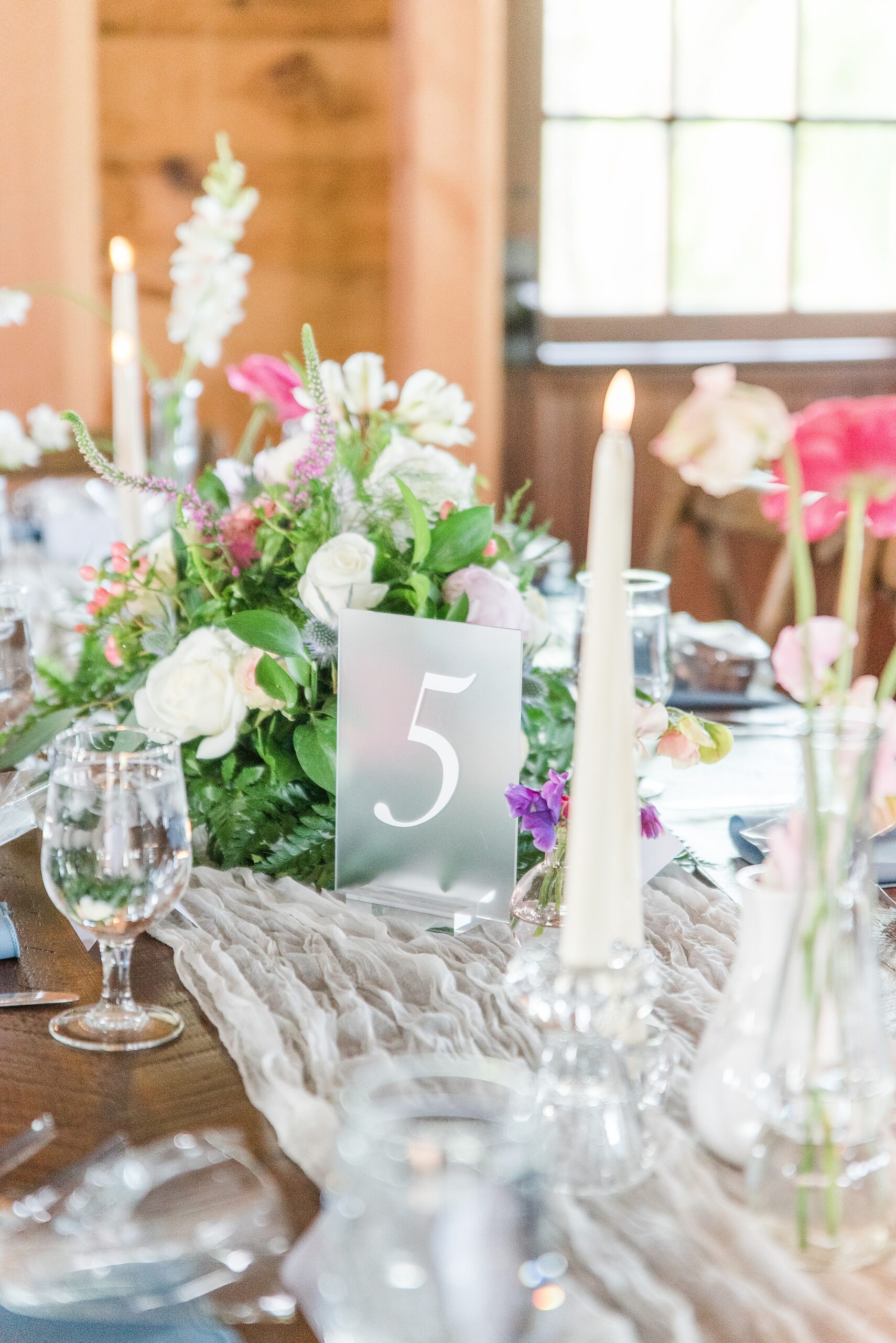 Details of a Bluebird Manor wedding reception table with florals on a wood table
