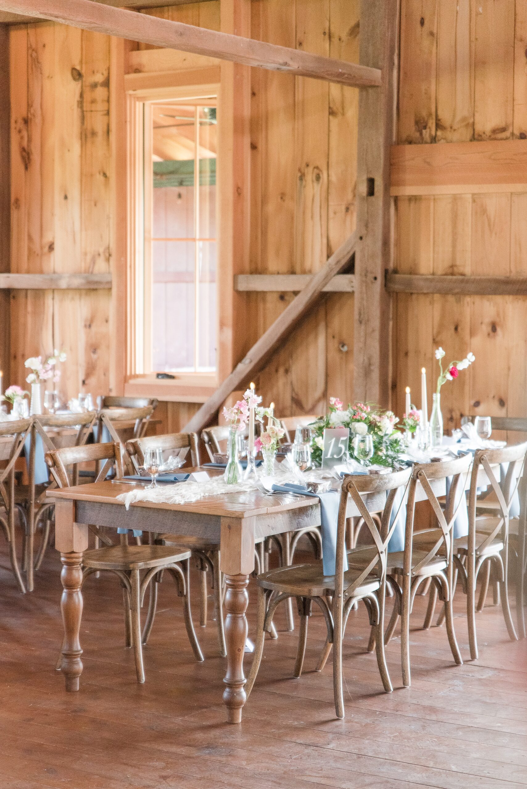 A view of a wooden table wedding reception set up at the Bluebird Manor wedding venue