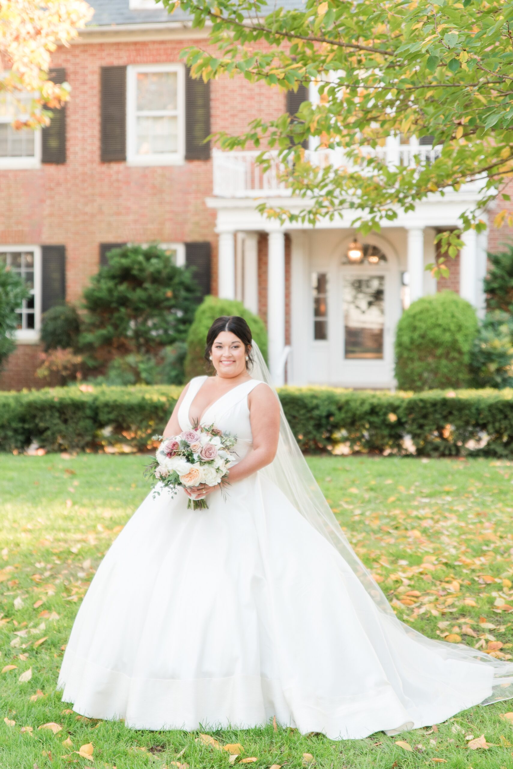 A bride smiles while standing in a lawn in front of the Brittland Estates Wedding venue