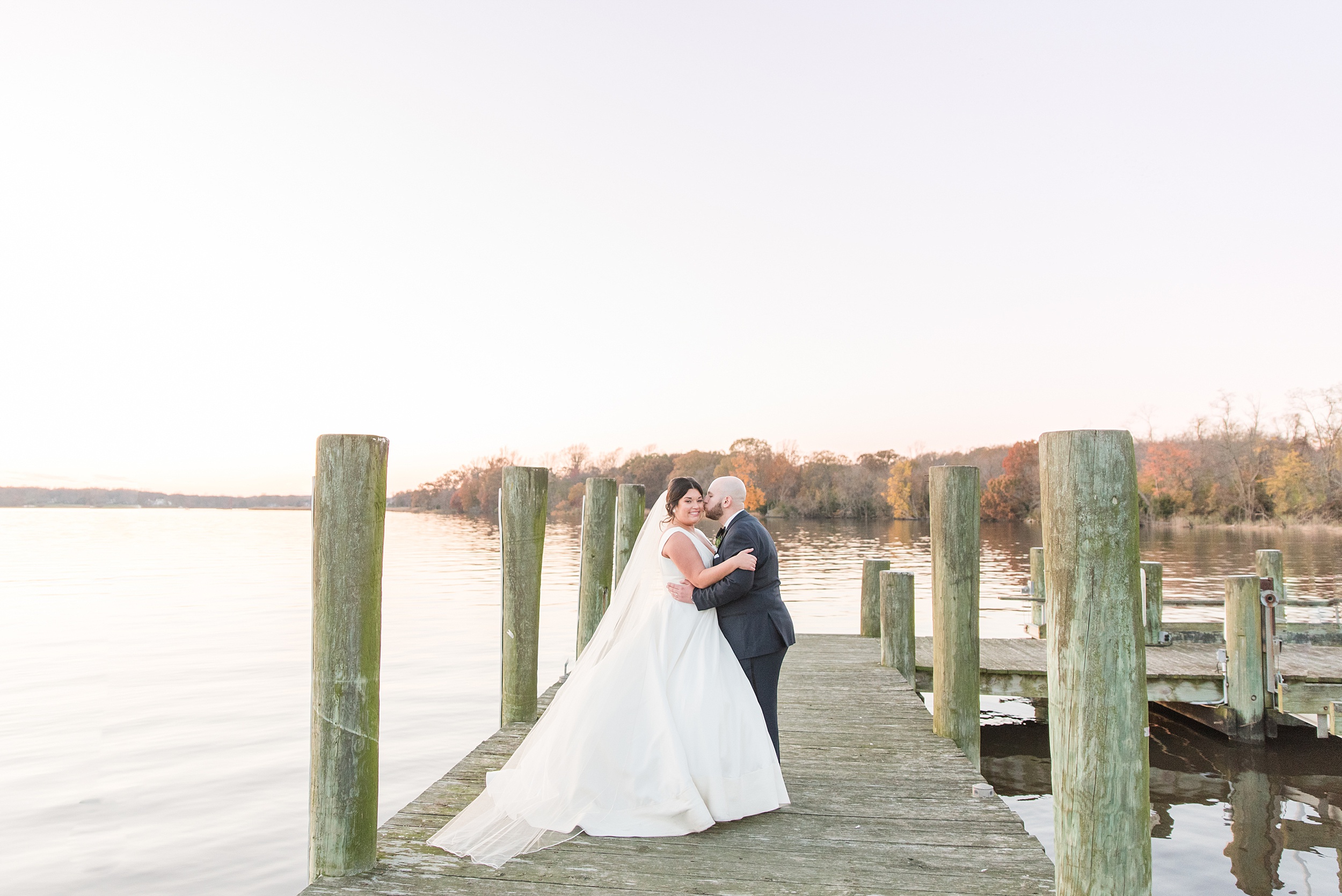 Newlyweds stand on a wooden dock at sunset during their Brittland Estates Wedding