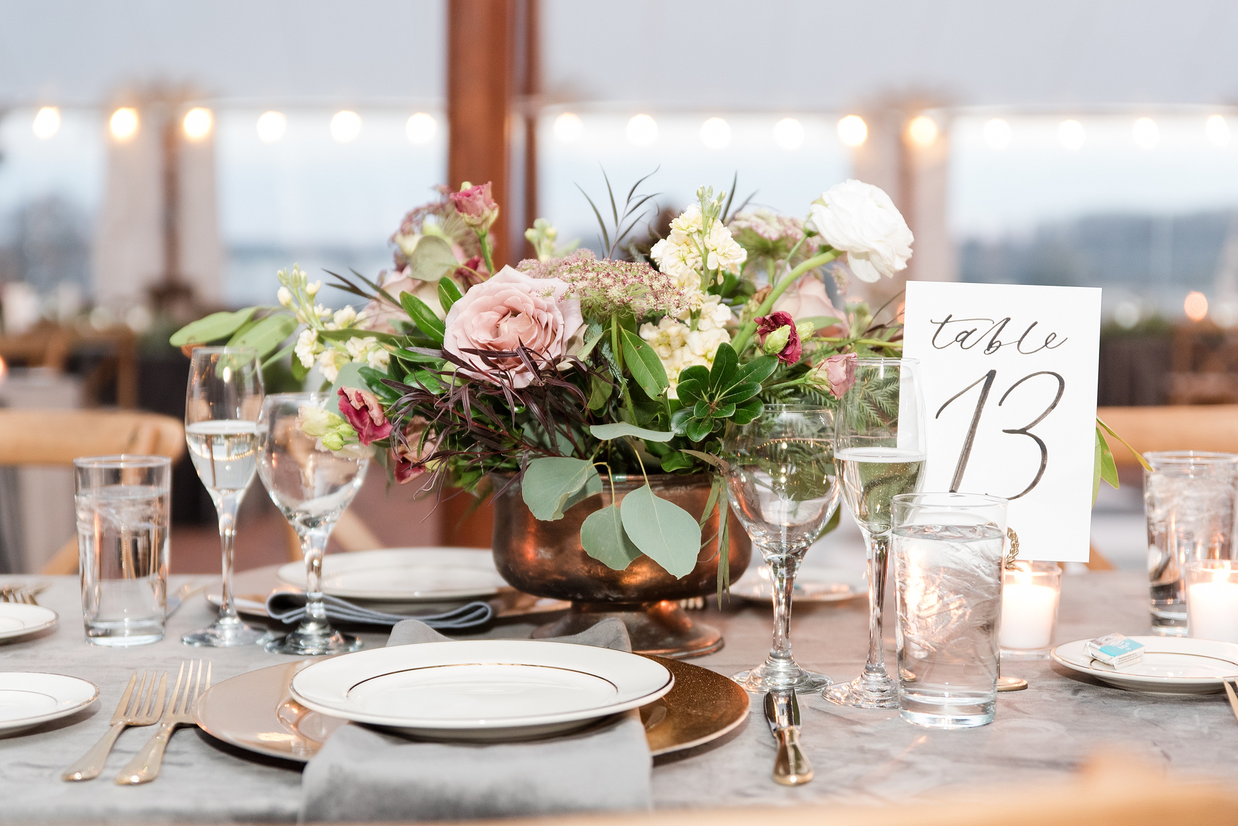 Details of a wedding reception table setting with a copper vase filled with flowers