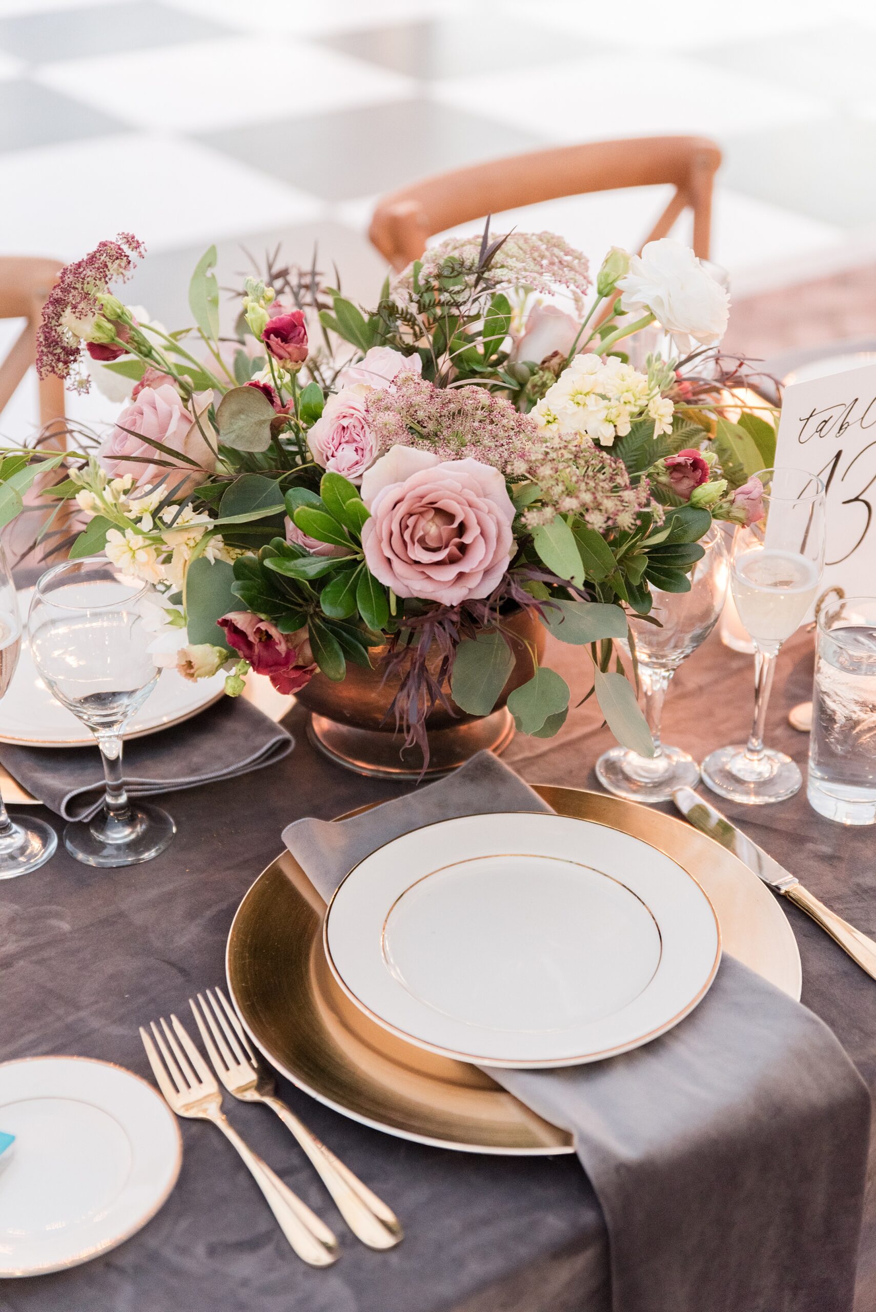 Details of a table setting with gold silverware and a pink floral at a Brittland Estates Wedding reception