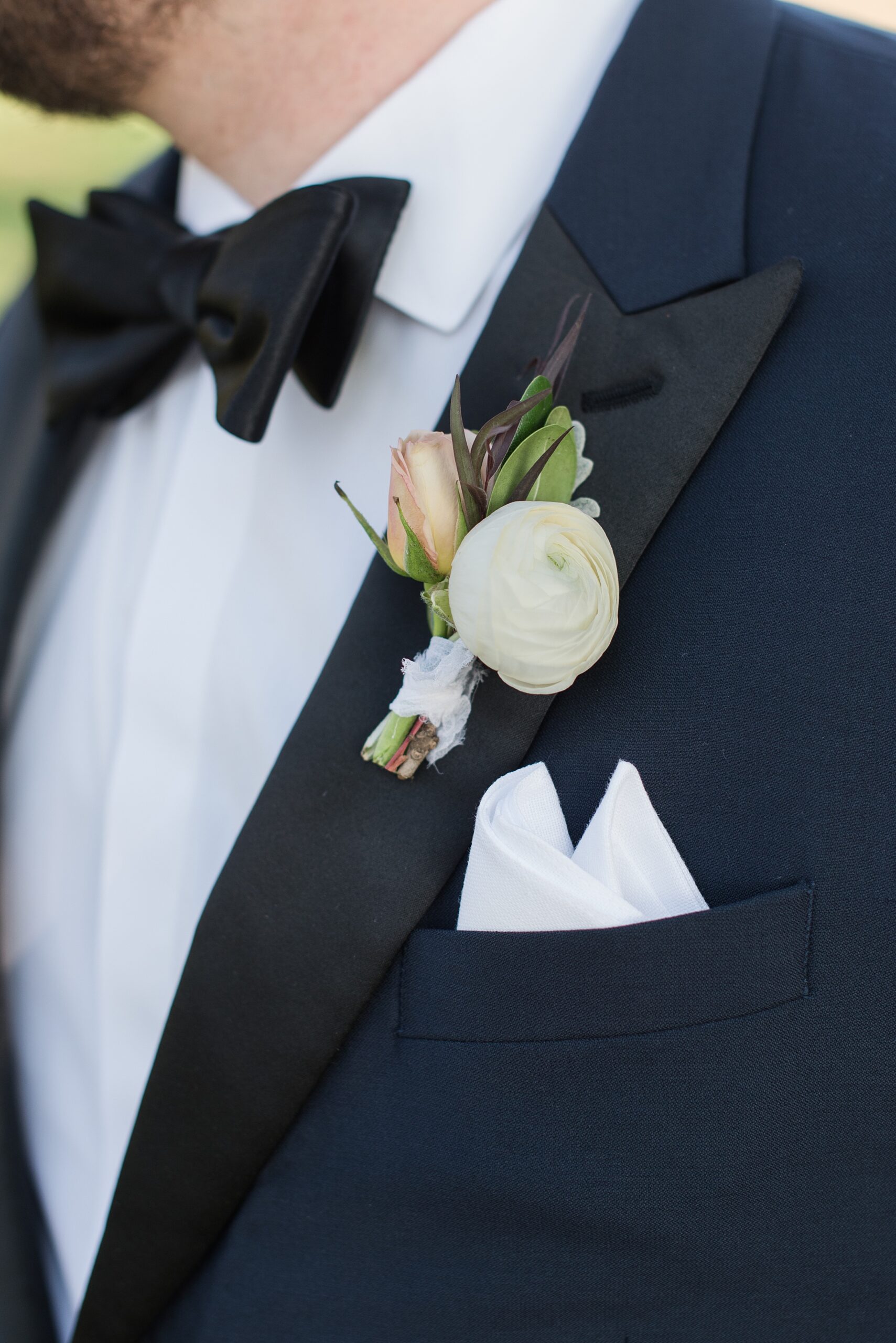 Details of a groom's boutonniere on a blue and black suit