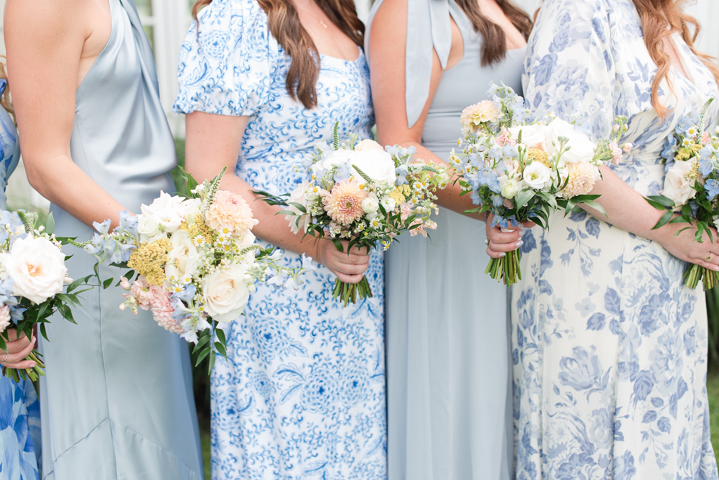 A group of bridesmaids stand holding their colorful bouquets