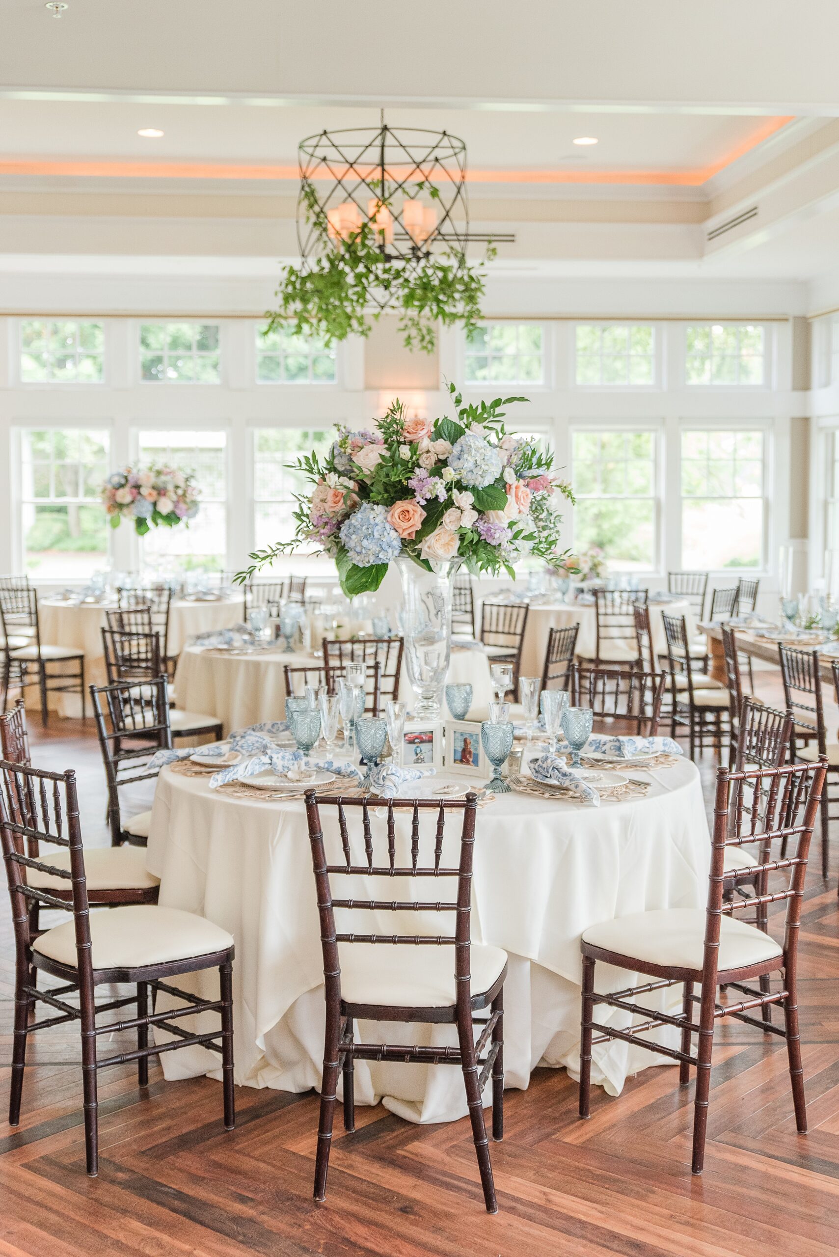 A view into a Chesapeake Bay Beach Club Wedding reception with natural wood chairs and white linens