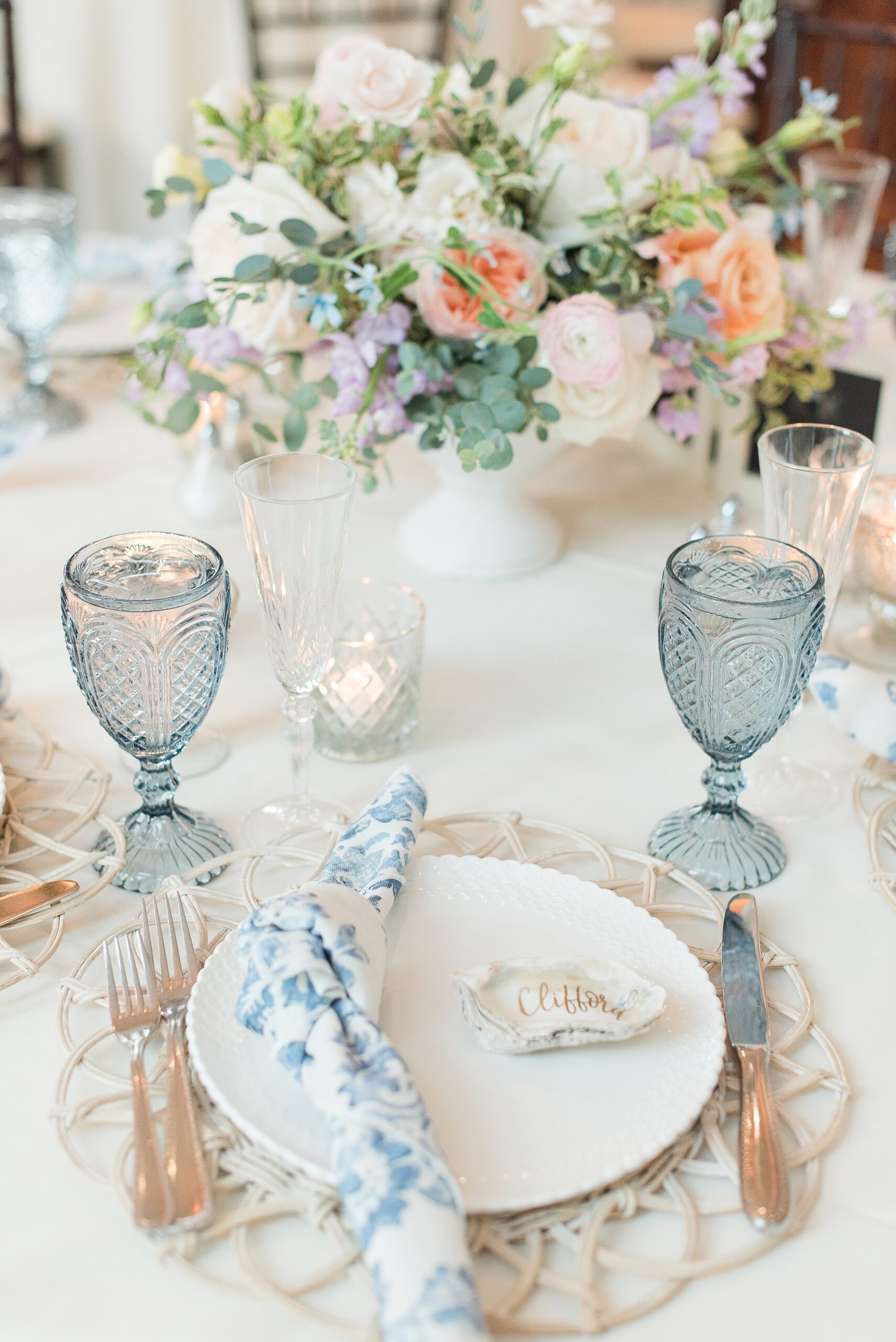 Details of a Chesapeake Bay Beach Club Wedding reception place setting with blue glasses and floral centerpiece