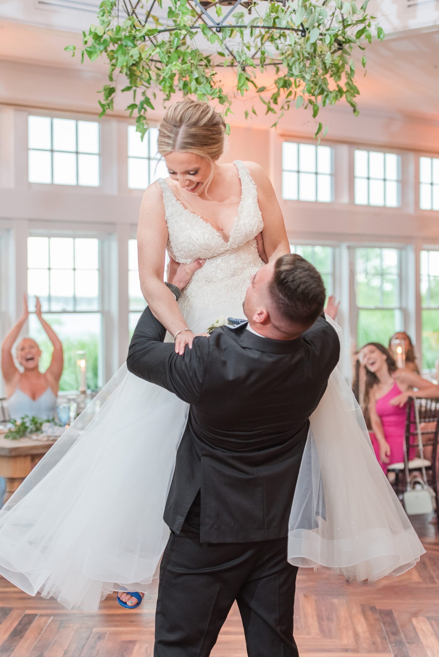 A groom lifts his bride while dancing for the first time at their Chesapeake Bay Beach Club Wedding reception