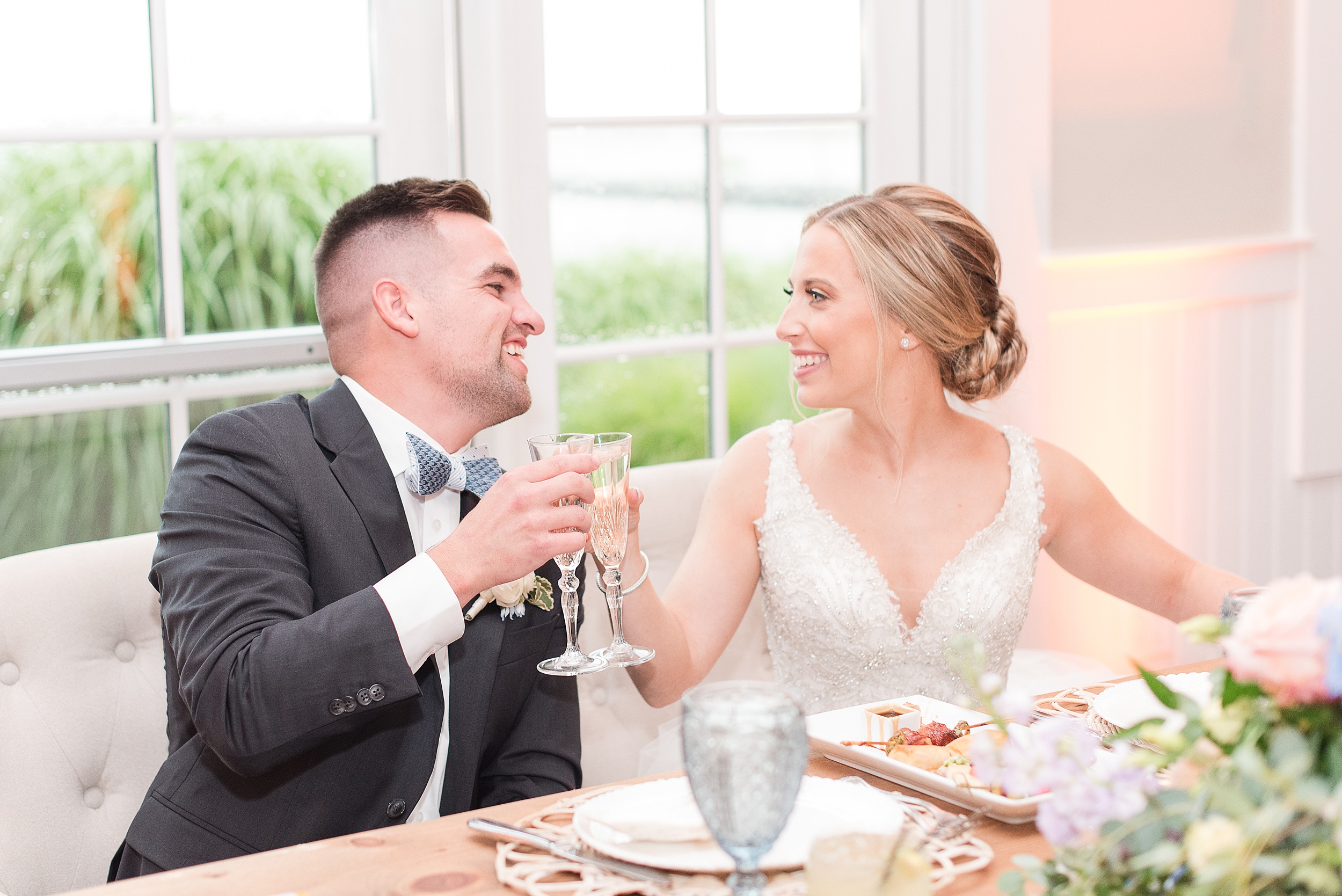 Newlyweds toast champagne flutes at their head table