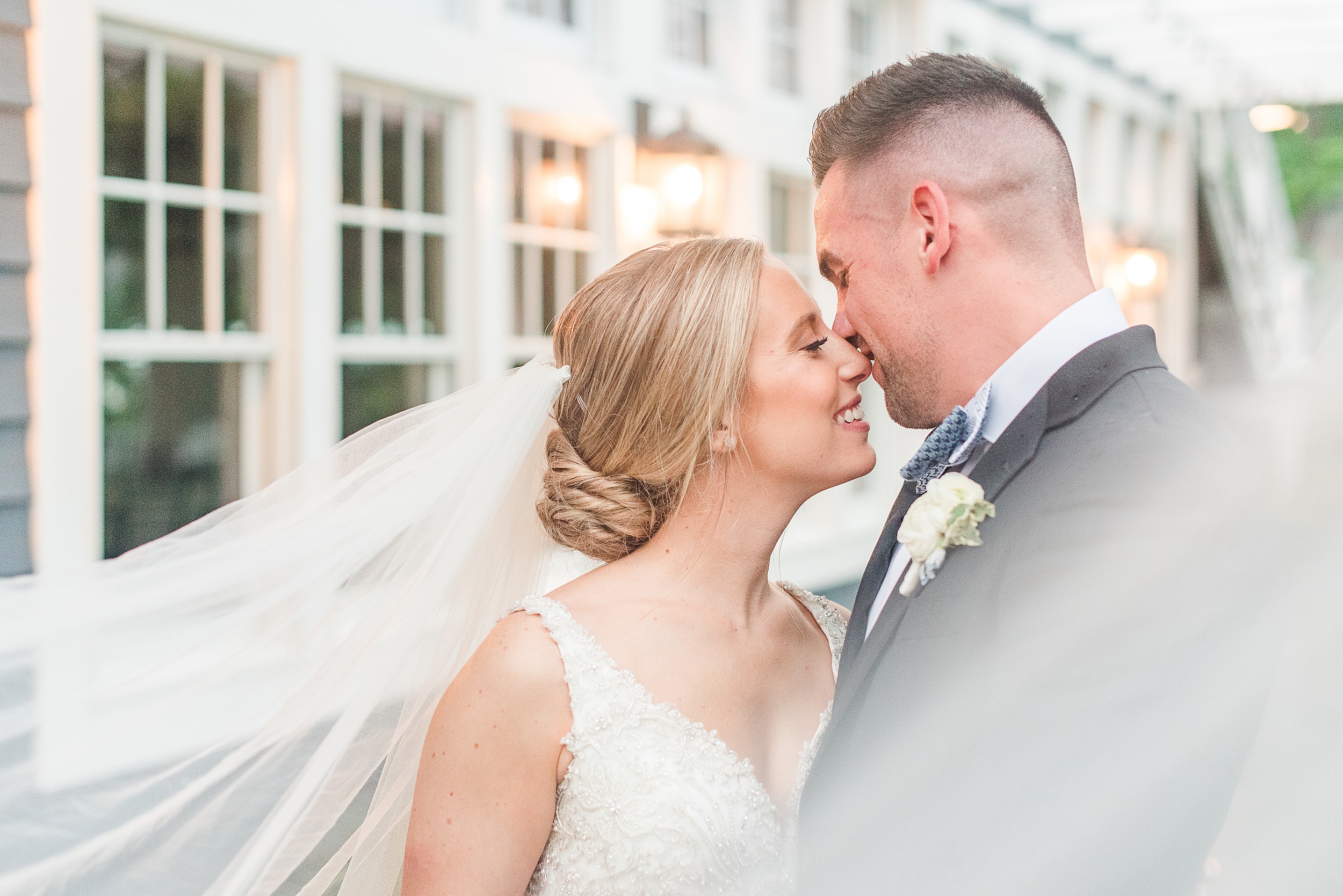 Newlyweds share an intimate moment on a patio with the veil blowing in the wind at their Chesapeake Bay Beach Club Wedding