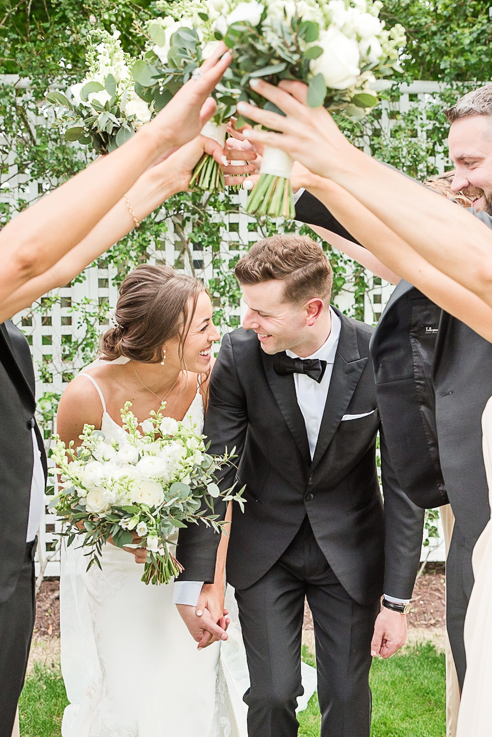 Newlyweds duck under an arch of their bridal party while holding hands at their Chesapeake Bay Beach Club Wedding