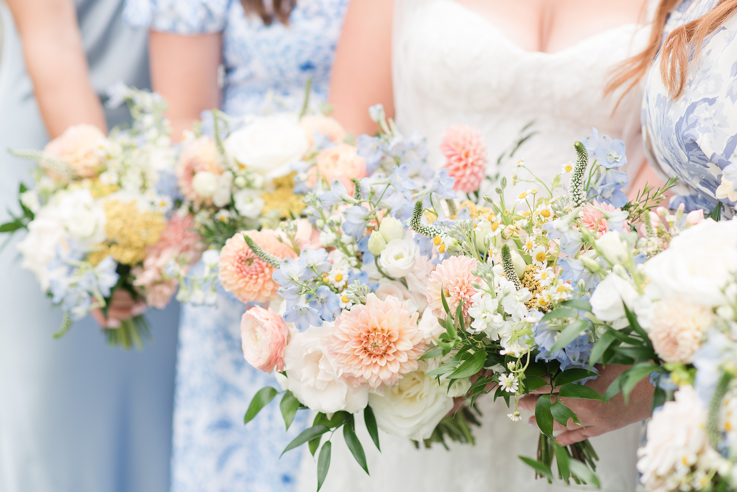 Details of a bride holding her pink and blue bouquet with her bridesmaids