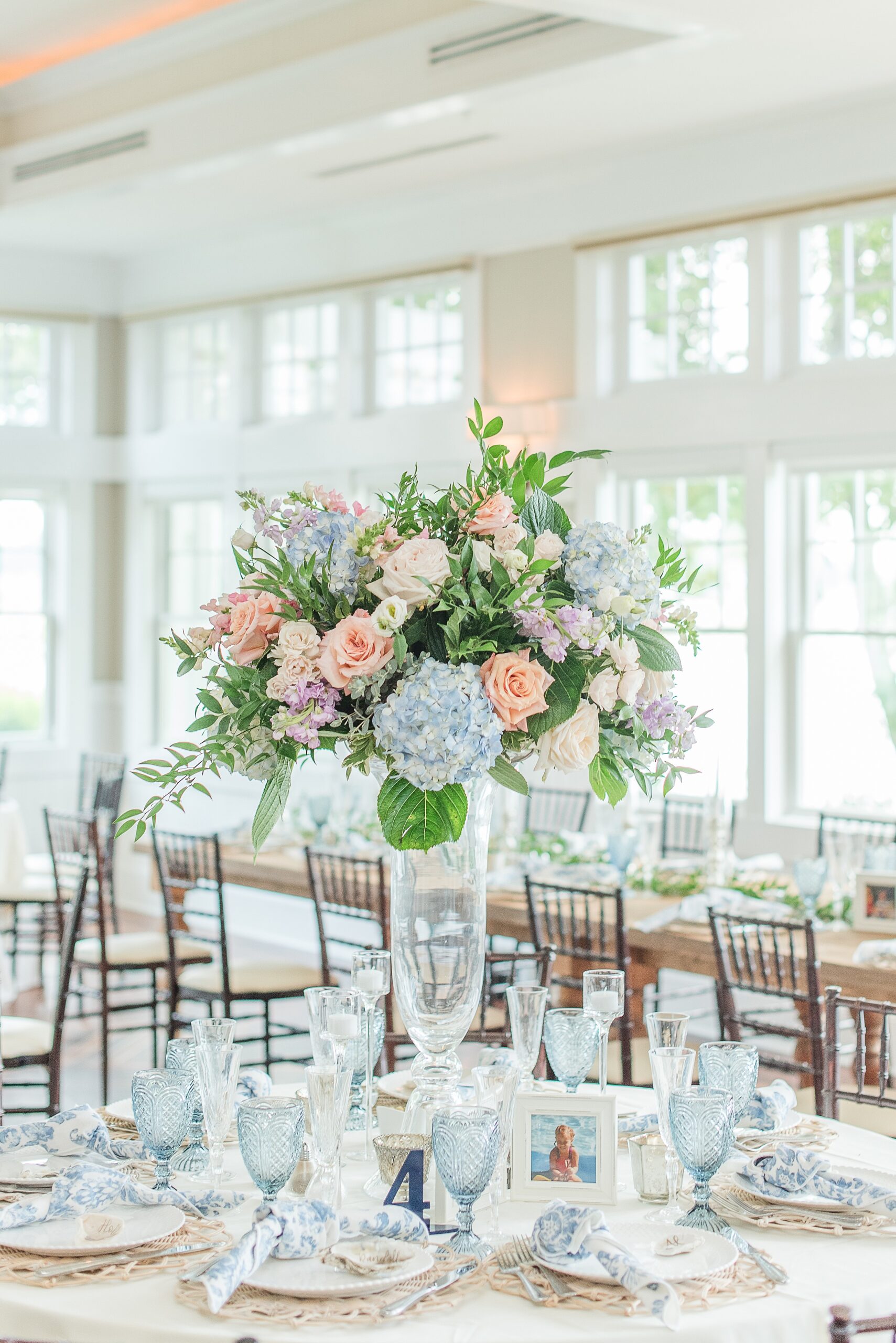 Details of a wedding reception table with tall floral centerpiece and blue glasses at a Chesapeake Bay Beach Club Wedding