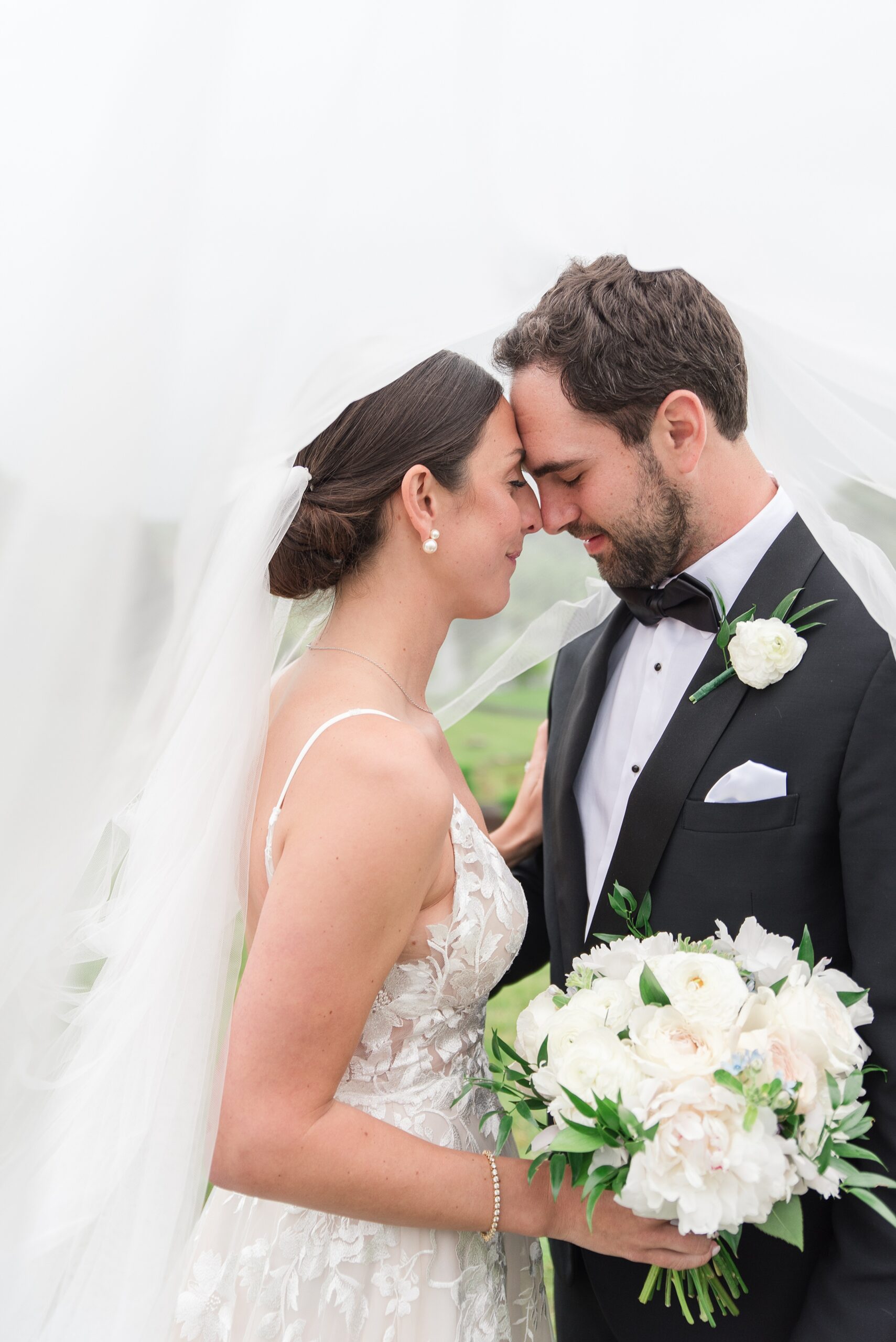 Newlyweds touch foreheads and smile while hiding under a veil at their Gramercy Mansion wedding