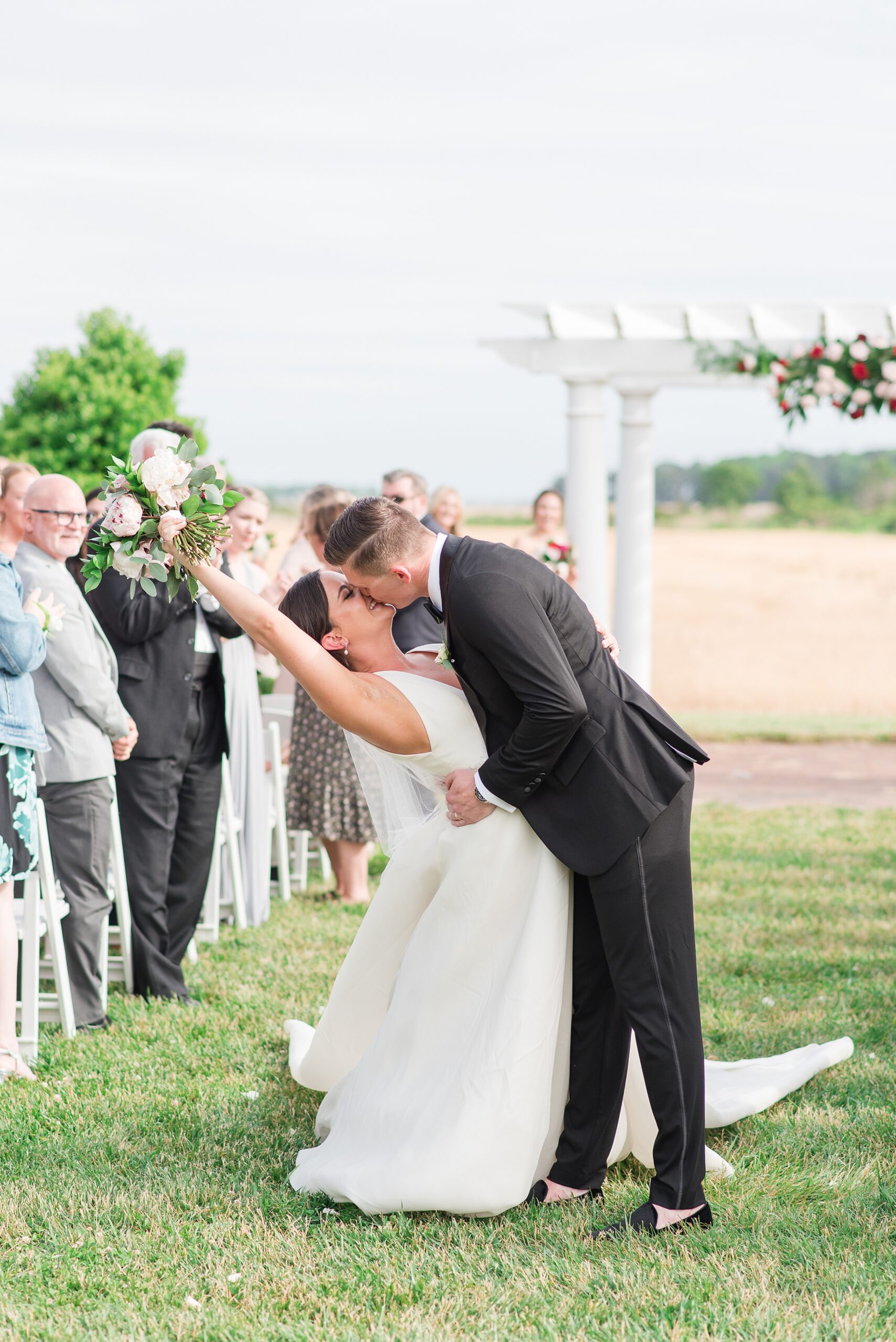 A groom dips his bride for a kiss in the aisle to end their Kent Island Resort Wedding ceremony