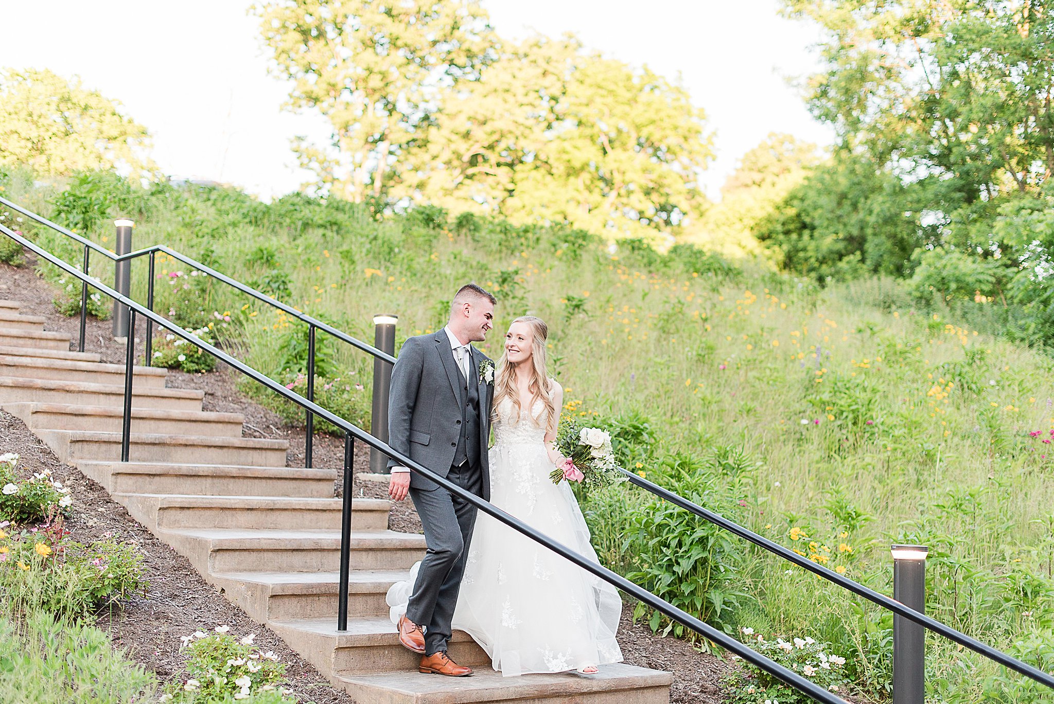 Newlyweds walk down a long set of park stairs smiling at each other at one of the Outdoor Wedding Venues In Baltimore
