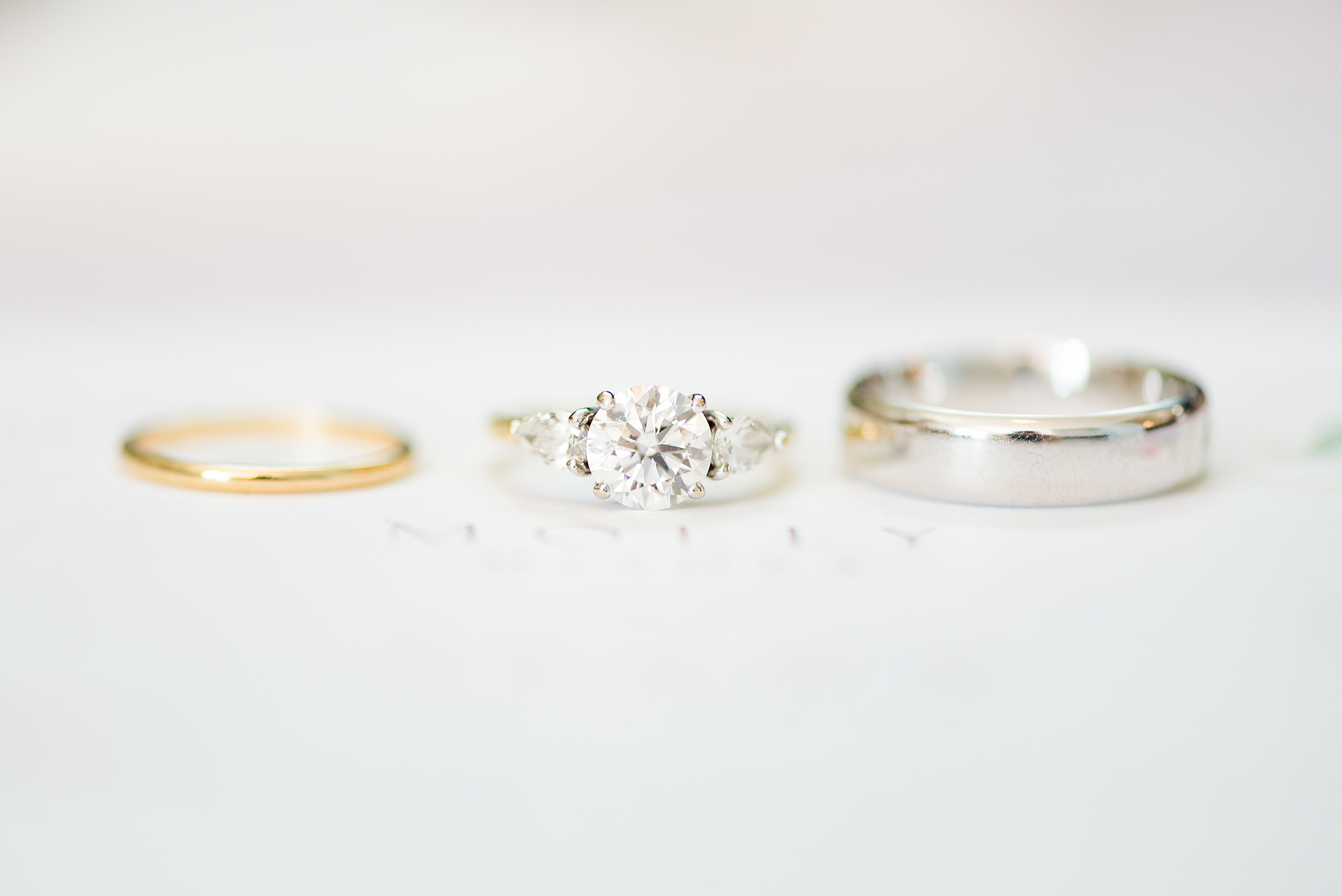Details of wedding bands and engagement ring sitting on a table