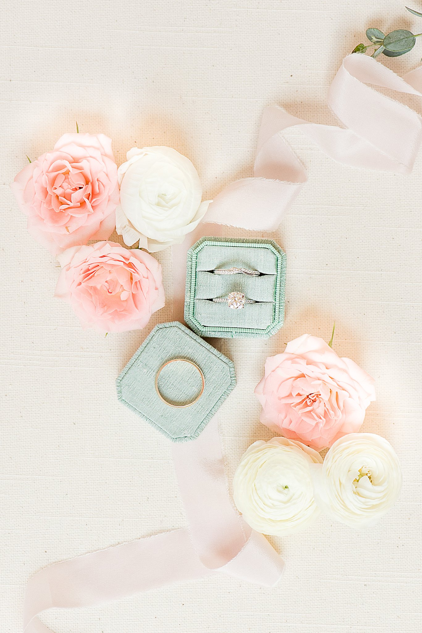 Details of wedding rings sitting in ring bow with pink and white flowers