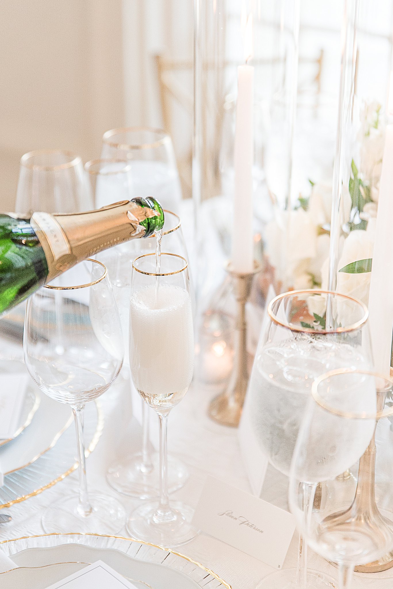Details of a bottle of champagne being poured into gold rimmed glasses by wedding planners Baltimore, MD