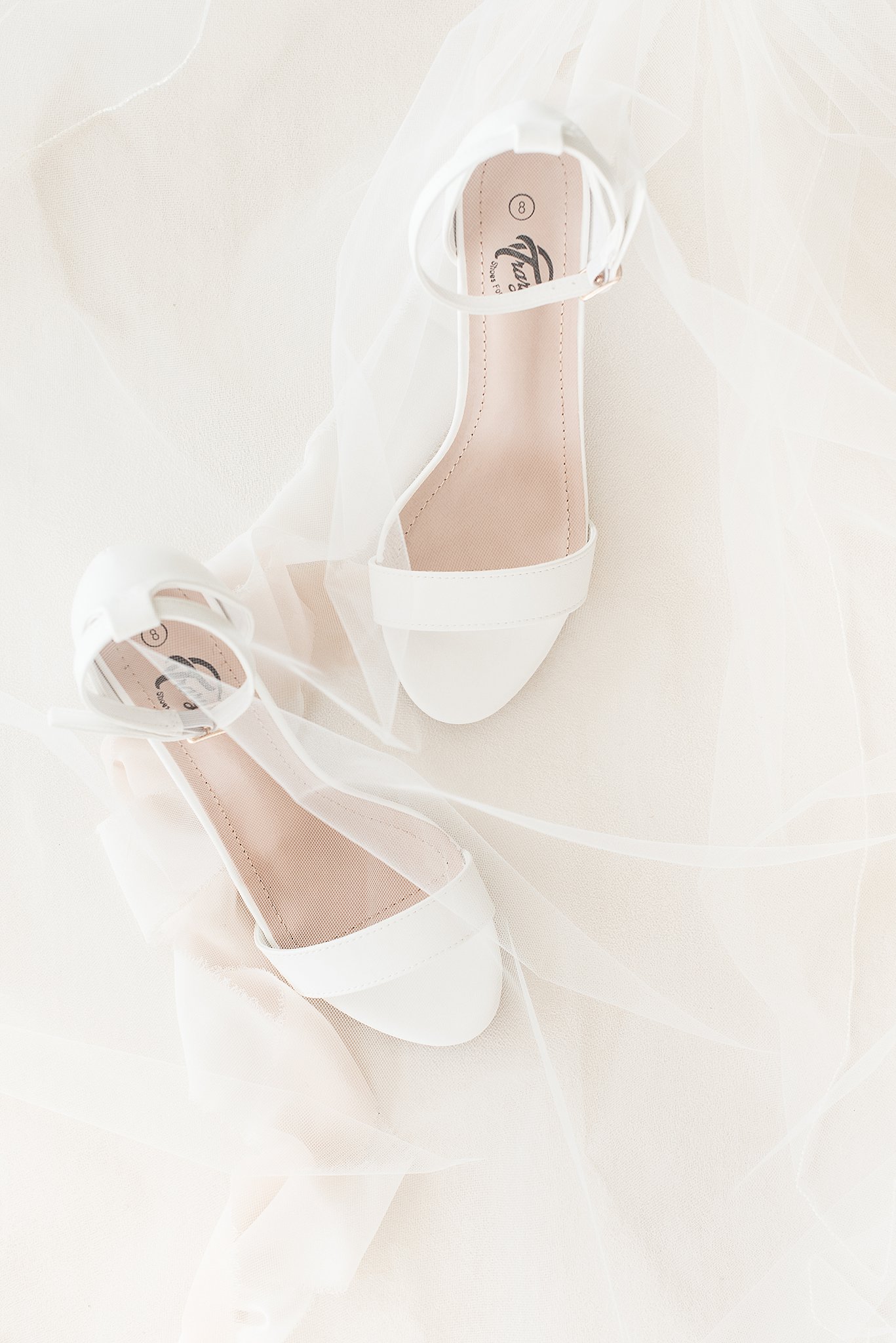 Details of white wedding shoes under a veil at an 1840s Plaza Wedding