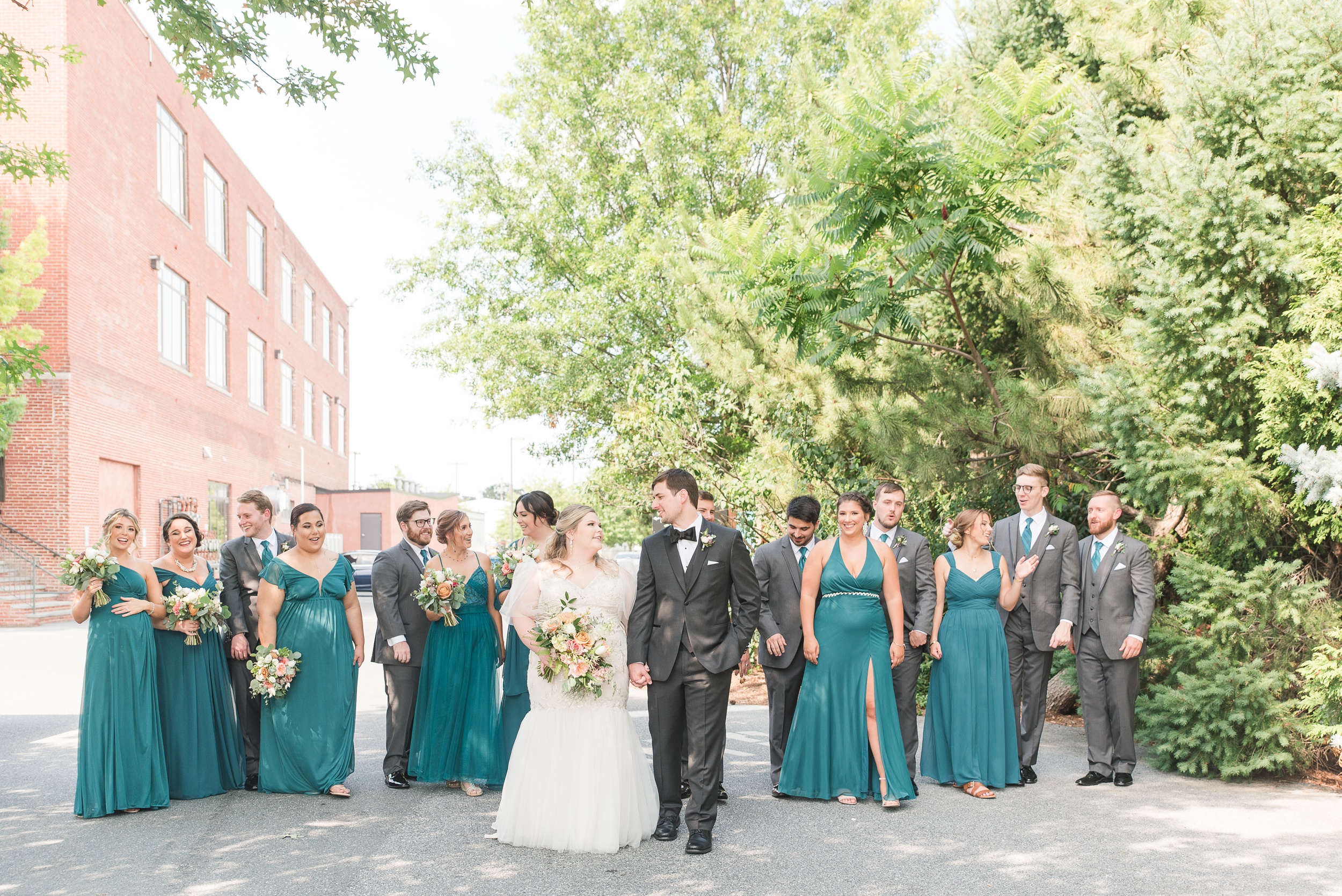 Newlyweds walk hand in hand through the alley with their large wedding party