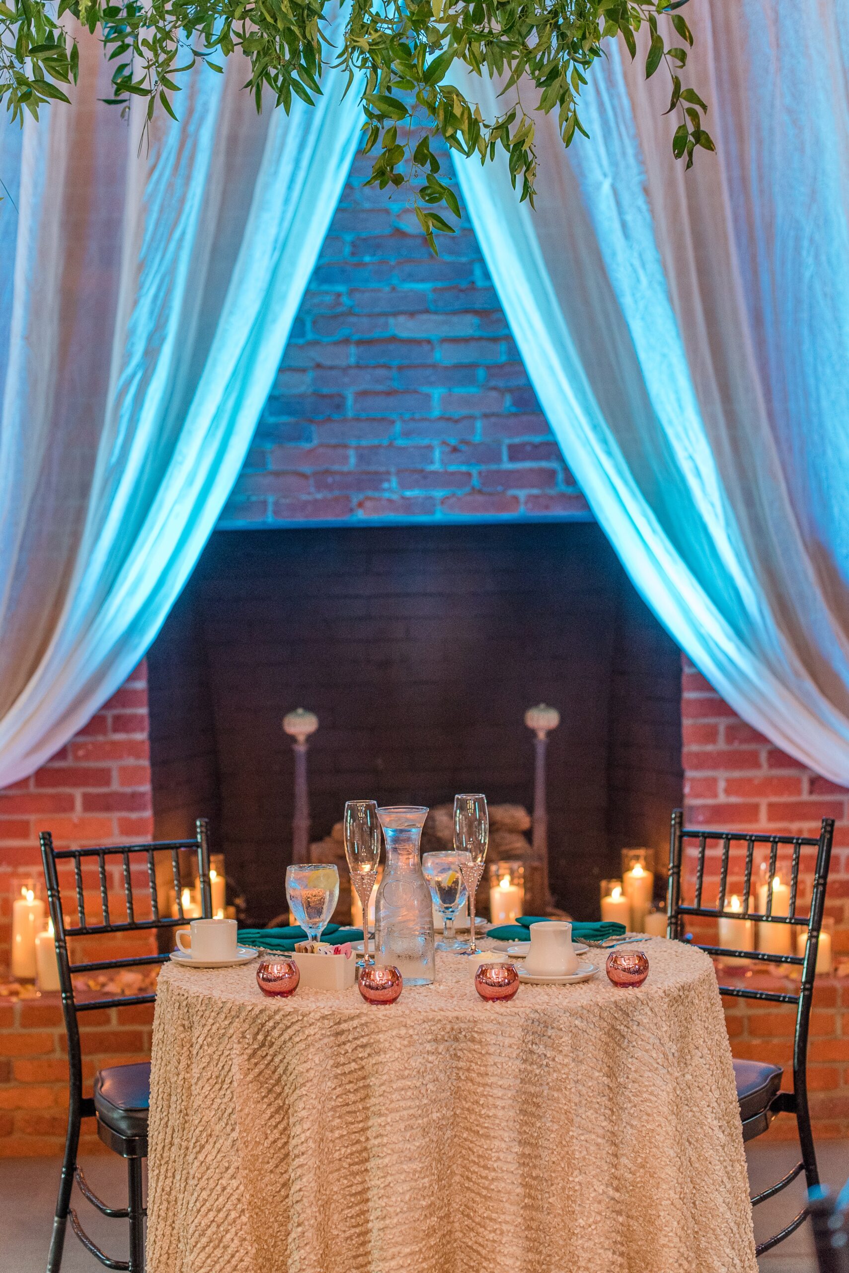 Details of a head table in front of a fireplace with blue uplighting at a Cork Factory Hotel Wedding