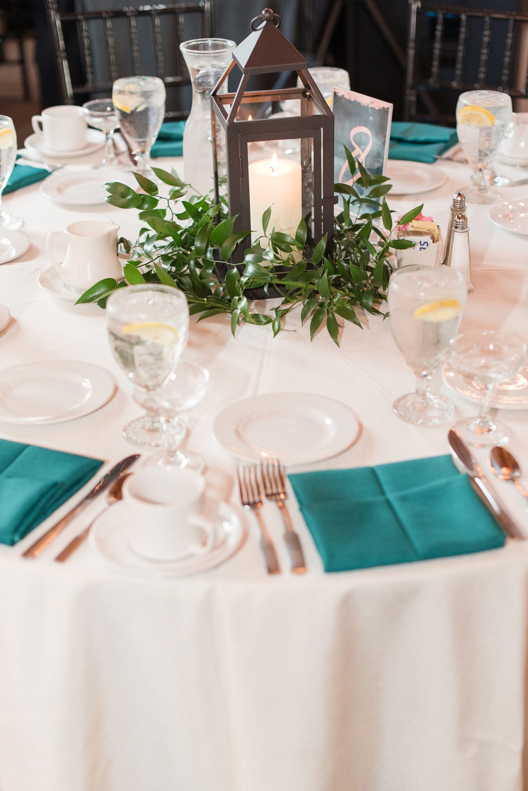 Details of a table setting with teal napkins and center candles