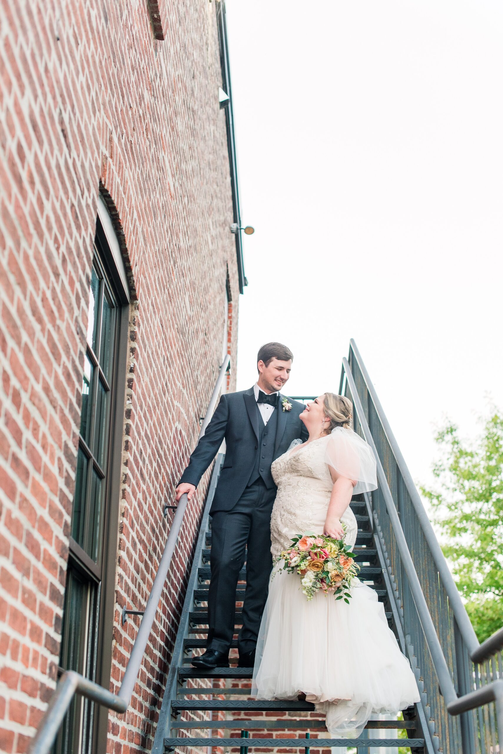 Newlyweds smile at each other while walking down some back stairs at their Cork Factory Hotel Wedding