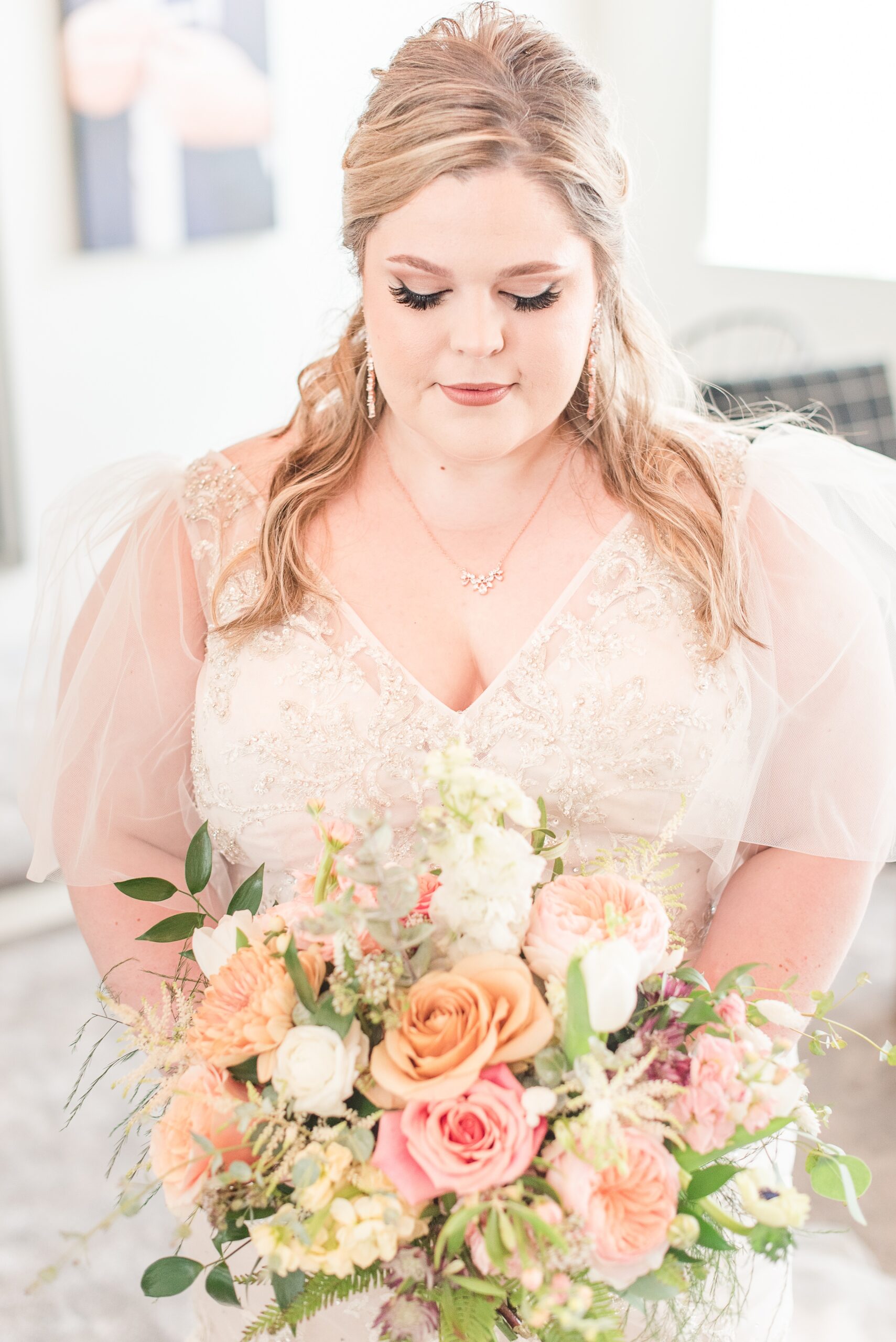 A bride smiles down to her colorful bouquet while standing in the getting ready room