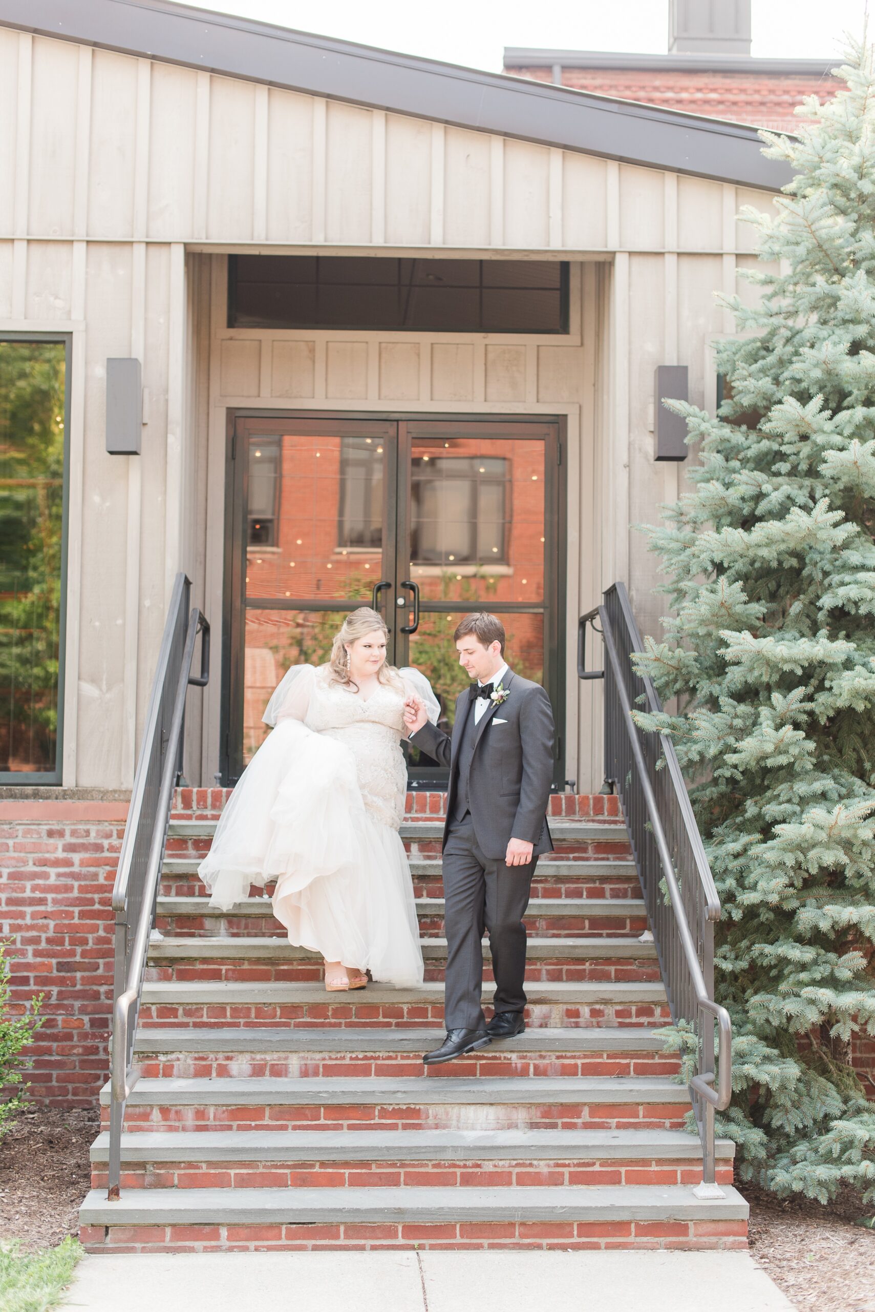 A groom walks his bride down some stairs by the hand during their Cork Factory Hotel Wedding