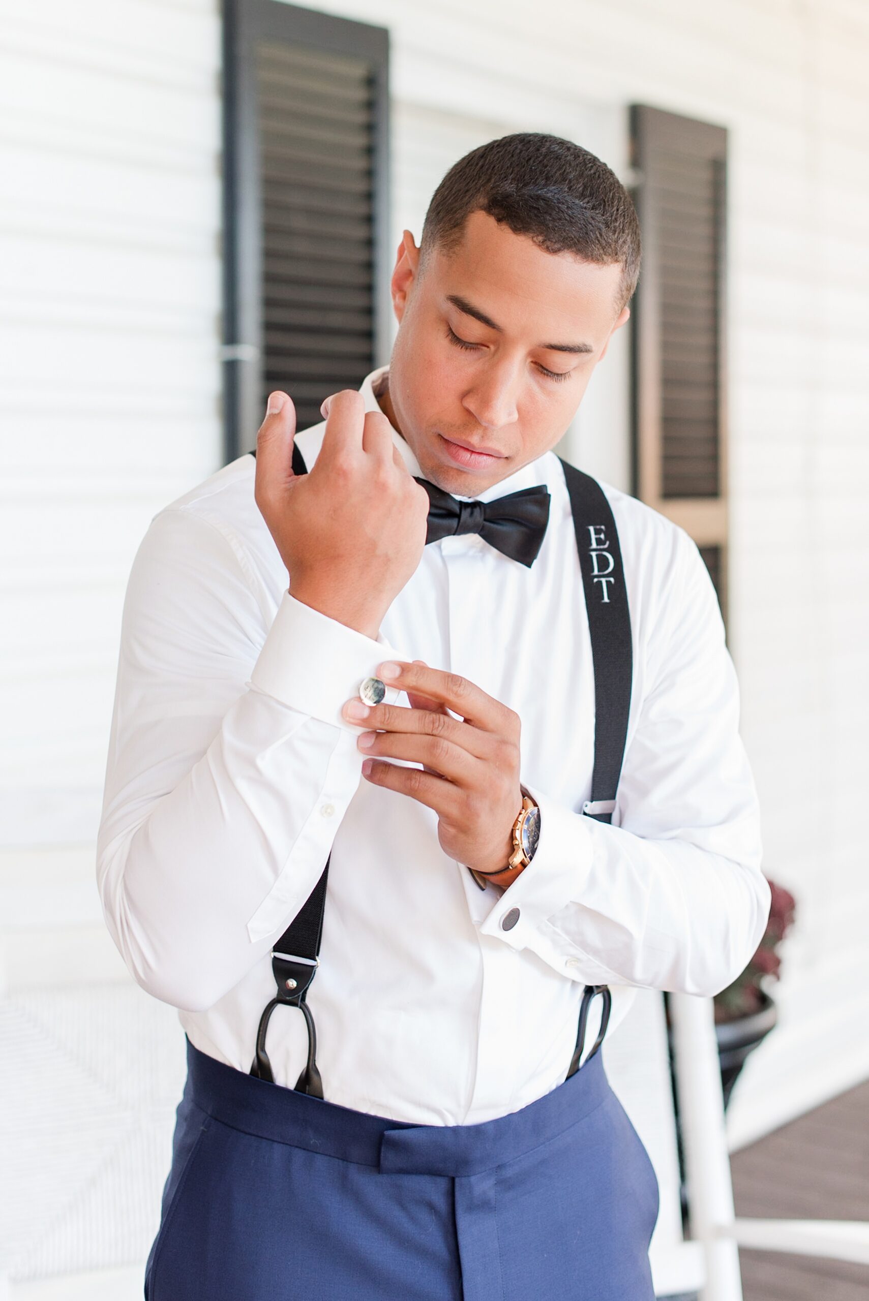 A groom puts on his cufflinks on a porch at his Herrington on the Bay Wedding