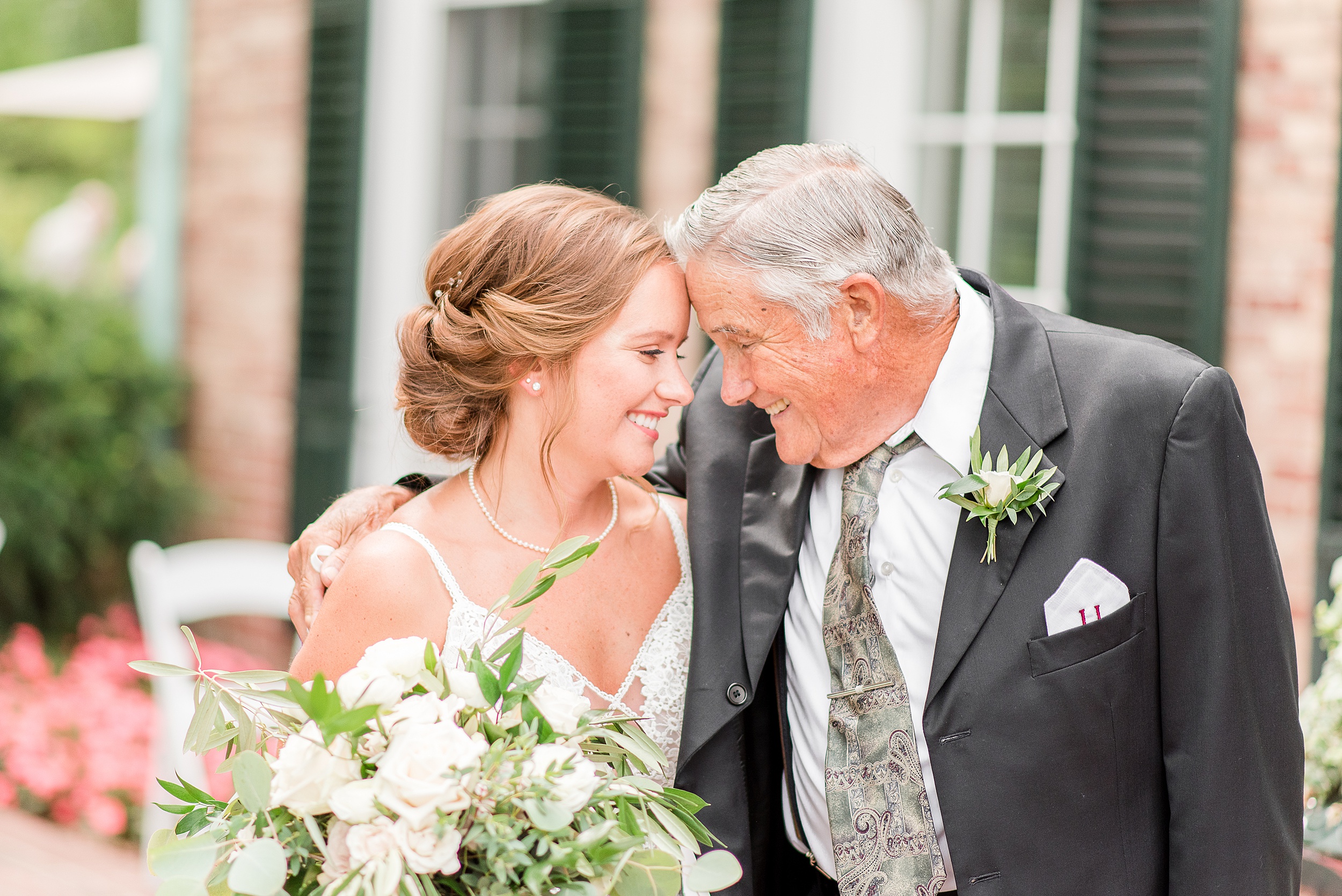 A bride smiles with her older male relative on a garden bench at her Kentlands Mansion Wedding