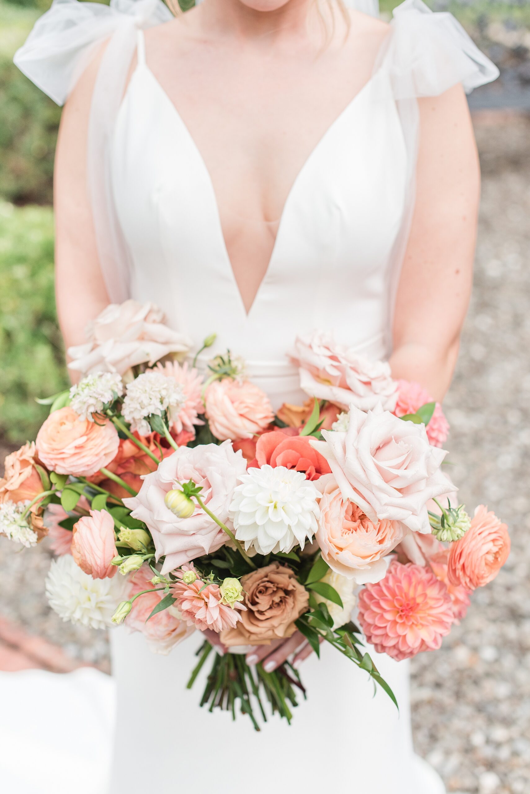 Details of a bride in a silk dress holding her pink bouquet