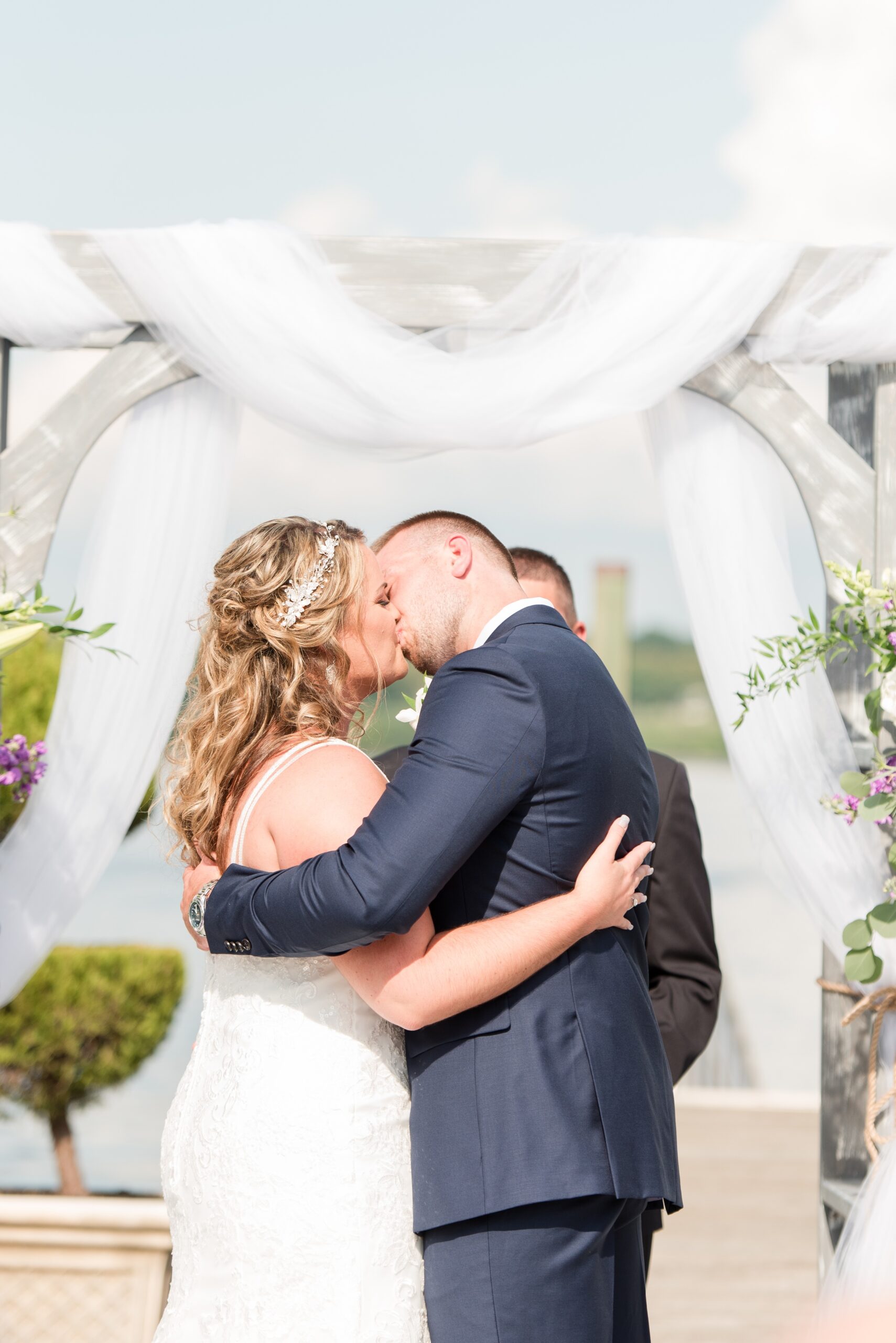 Newlyweds kiss at the altar under the arbor to end their La Banque de Fleuve Wedding ceremony