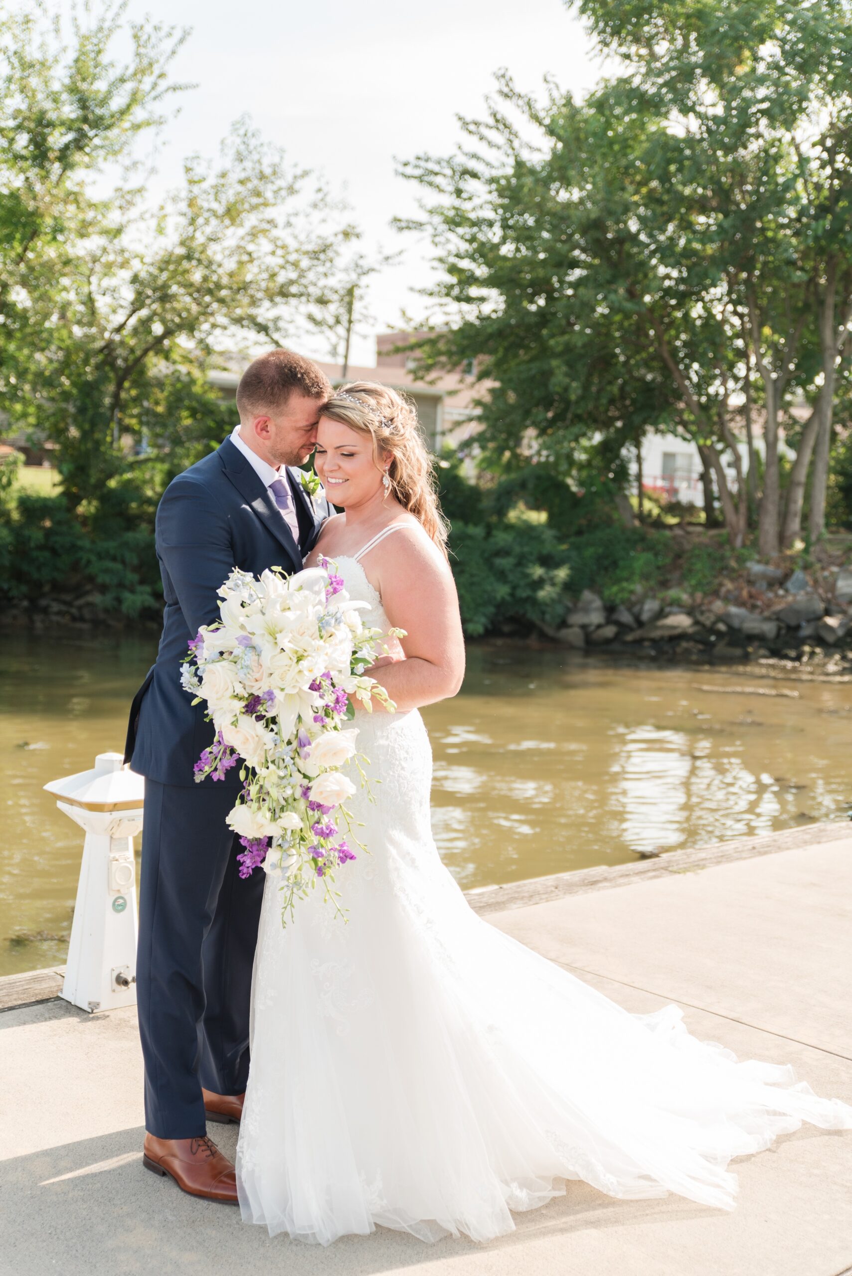 Newlyweds share an intimate moment while standing on a dock at their La Banque de Fleuve Wedding