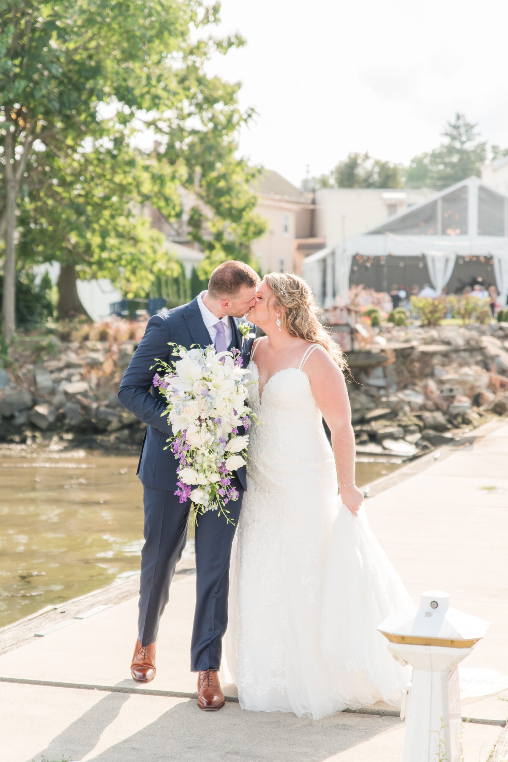 A bride and groom kiss while walking on a long dock