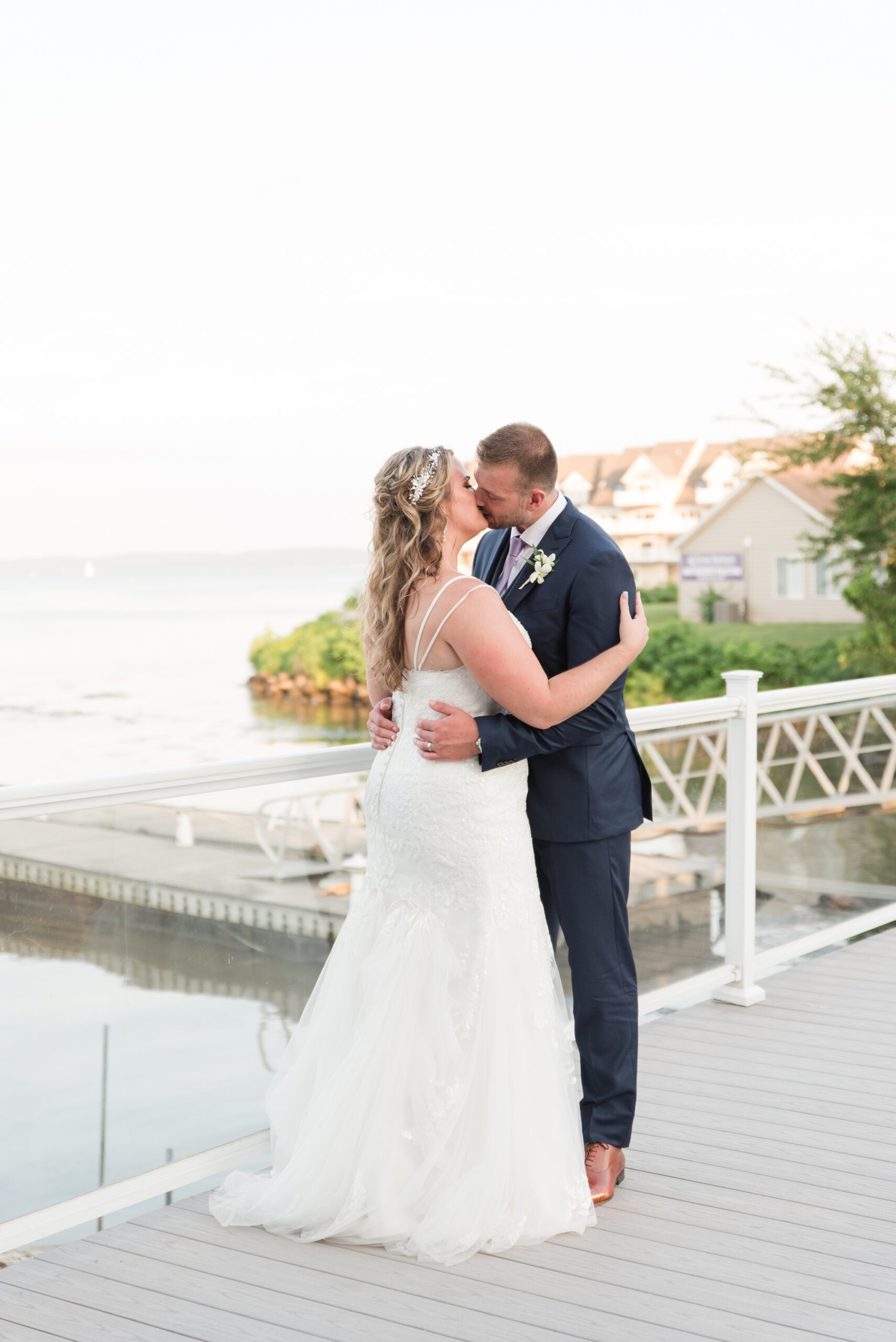 Newlyweds kiss on a waterfront dock during their La Banque de Fleuve Wedding