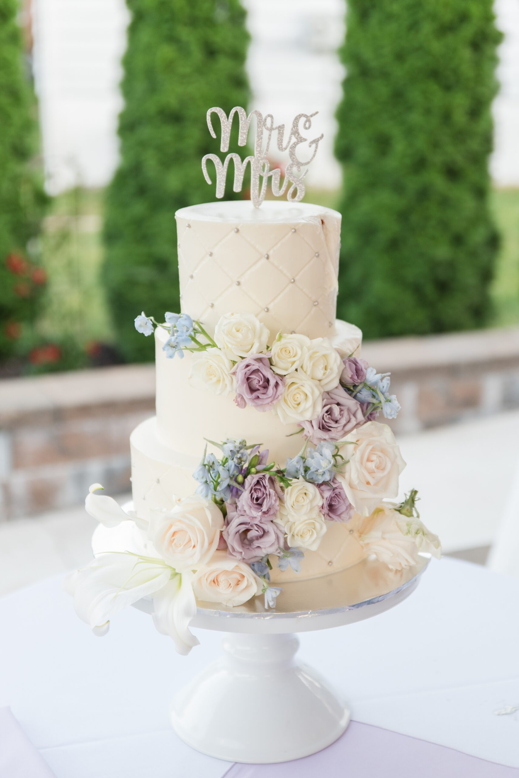 Details of a three tier wedding cake covered in roses
