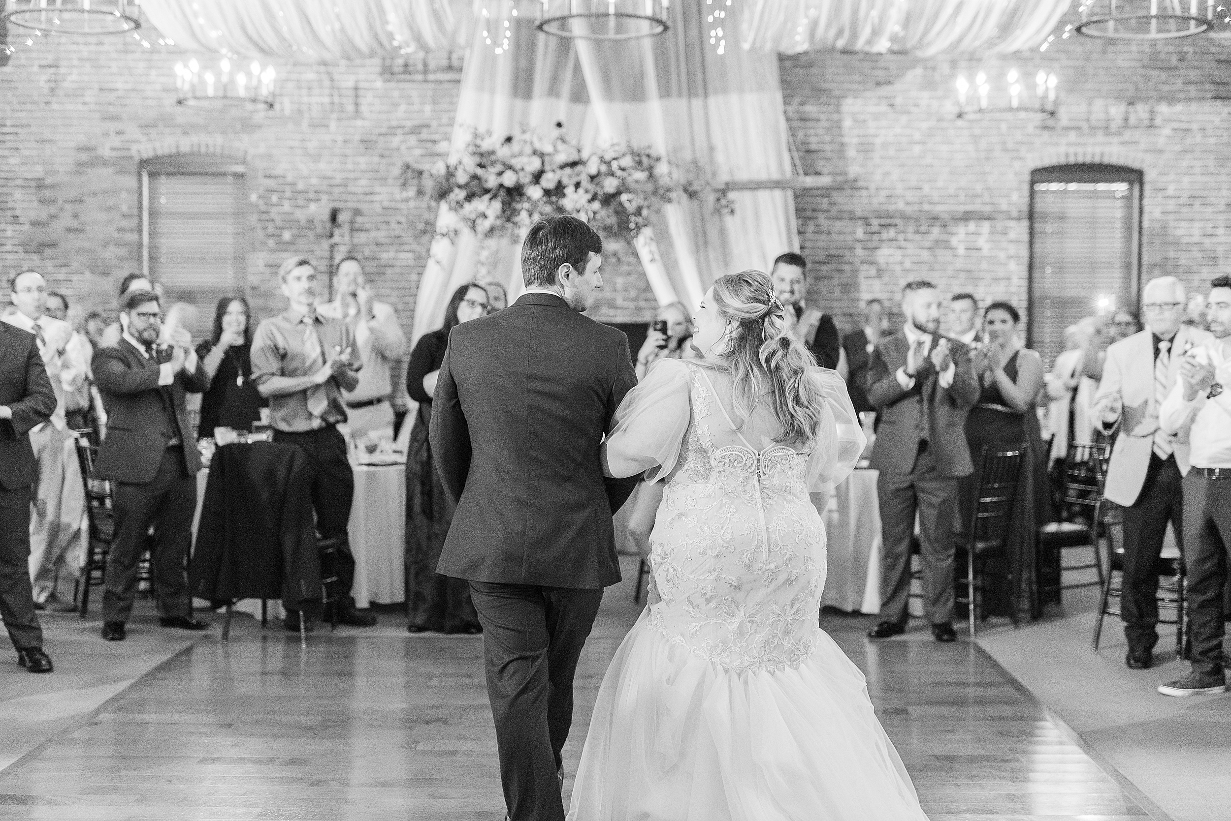 Newlyweds smile at each other while entering the dance floor for their first dance