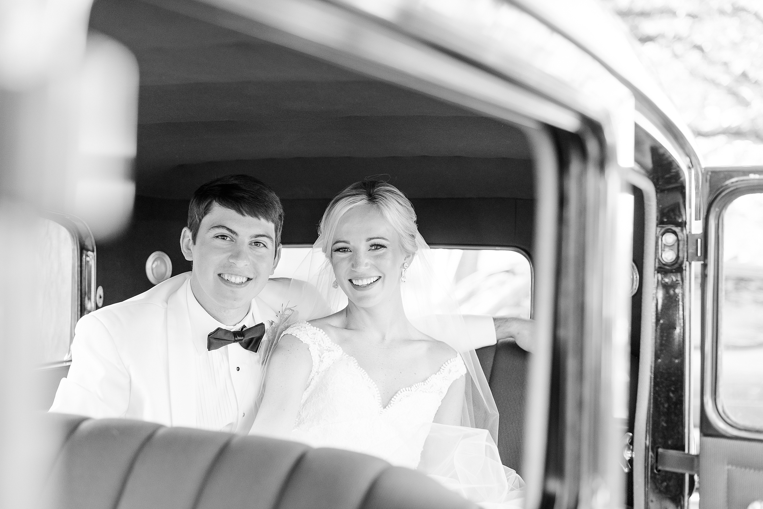 Newlyweds sit in the back of a vintage car smiling at their Swan Harbor Farm Wedding