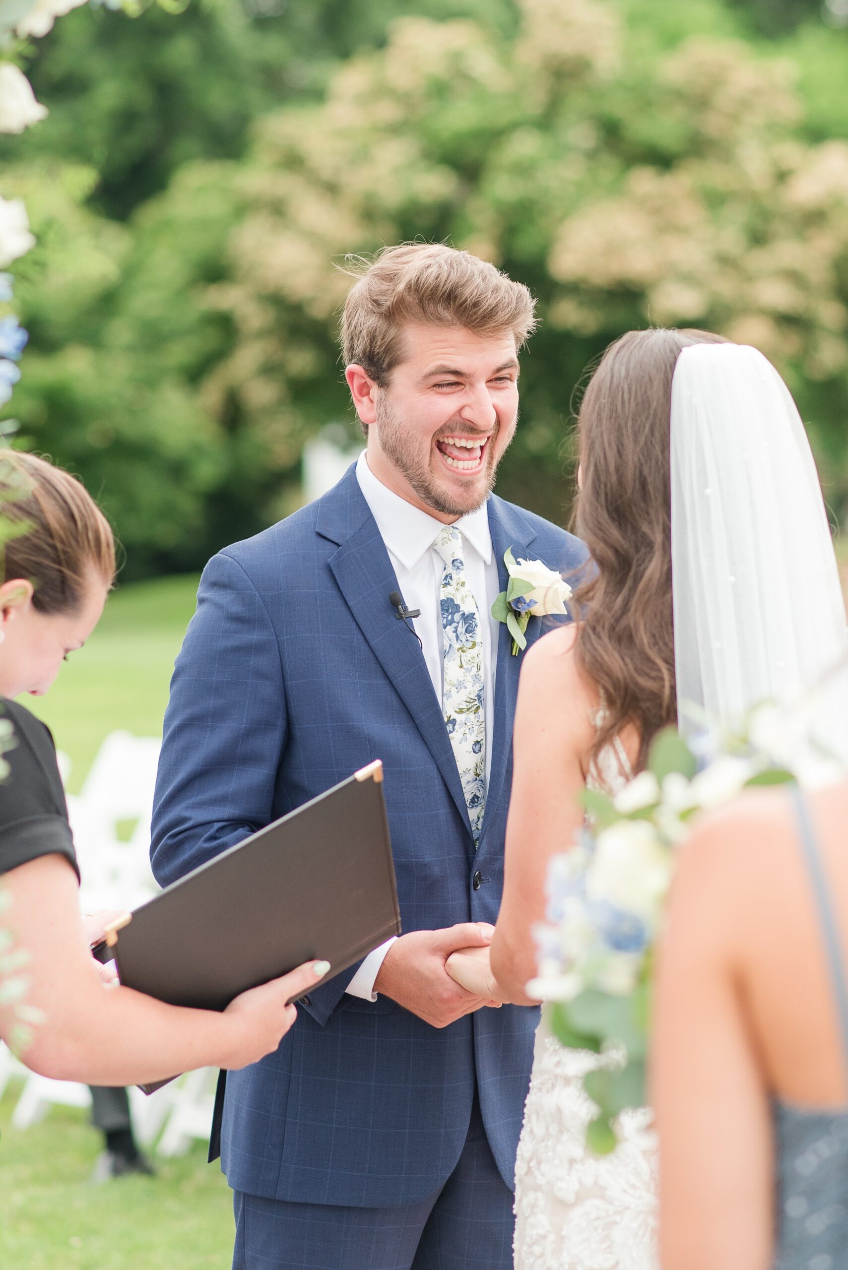 A groom laughs big during the vows at his wedding ceremony