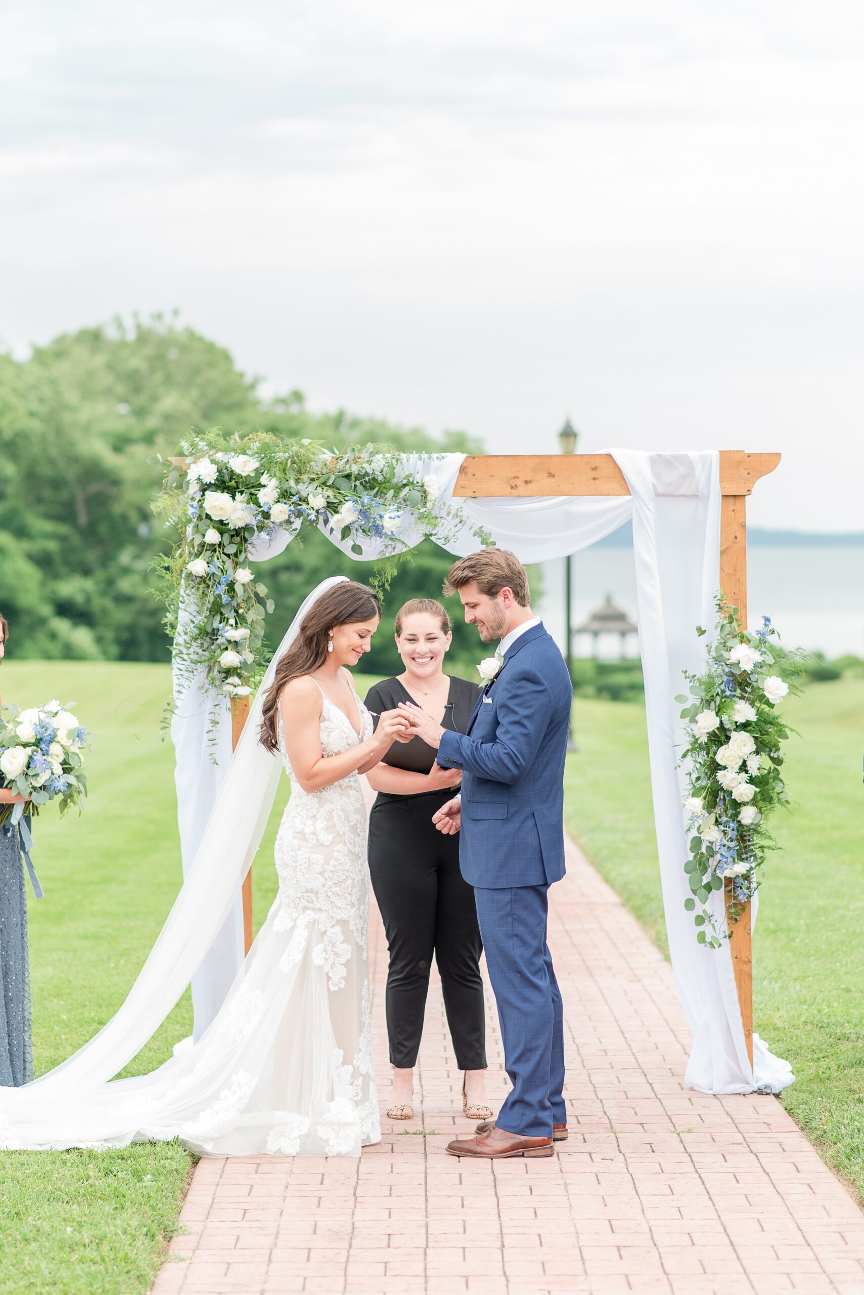 A bride puts the ring on her groom's finger during their outdoor Swan Harbor Farm Wedding ceremony