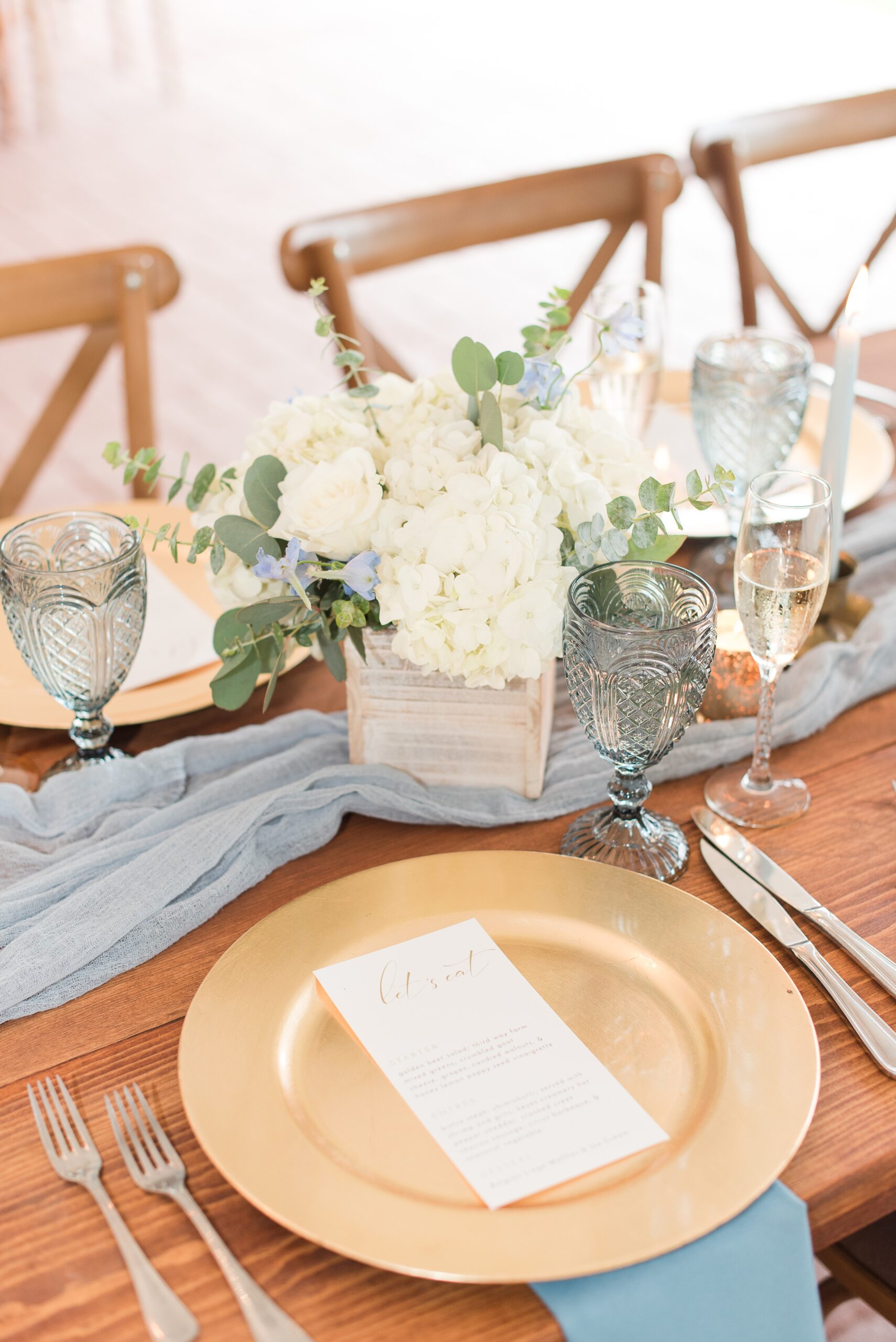 Details of a wooden wedding reception table with white florals at a Swan Harbor Farm Wedding
