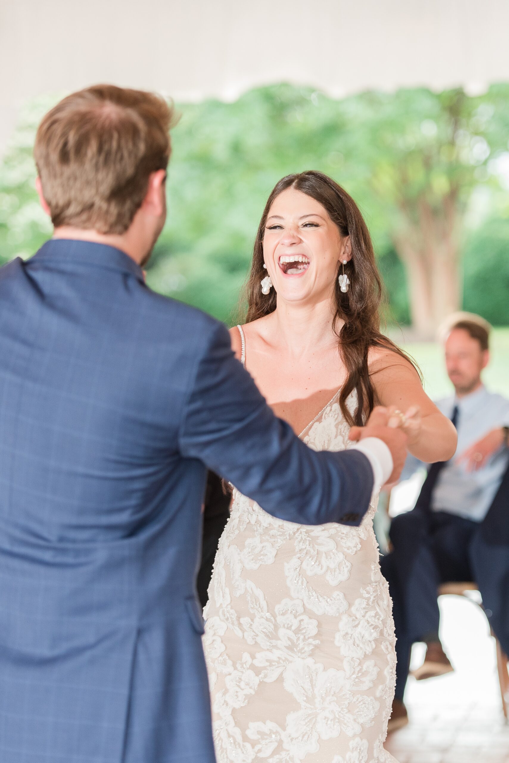A bride laughs big while dancing with her groom on the dance floor